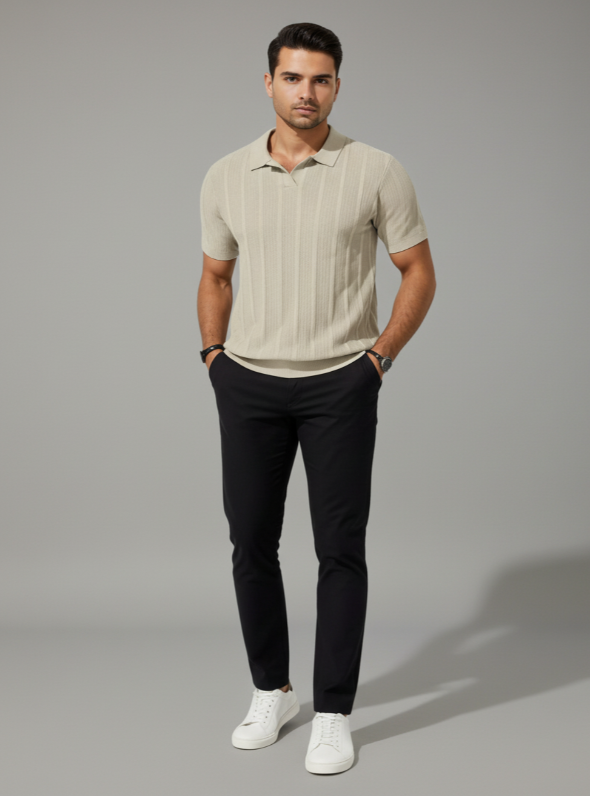Man wearing a beige striped polo shirt and black pants on a gray background