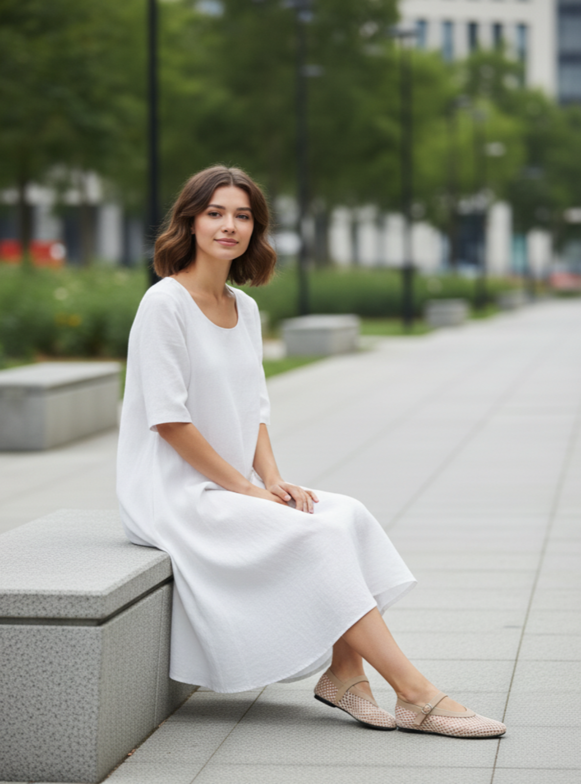 Woman in a white dress sitting on a bench outdoors with blurred background