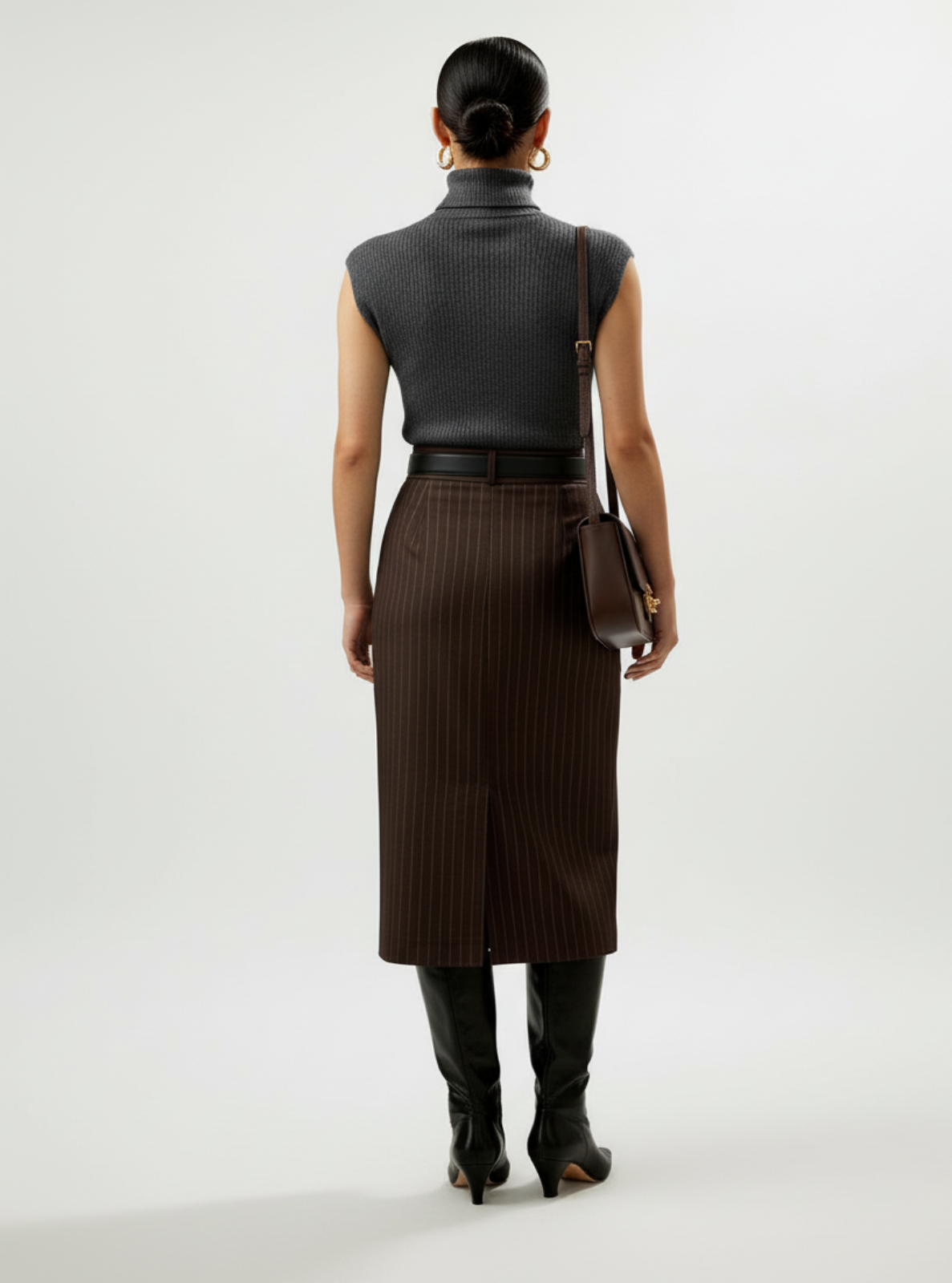 Person wearing a black sleeveless top and brown skirt with a white background