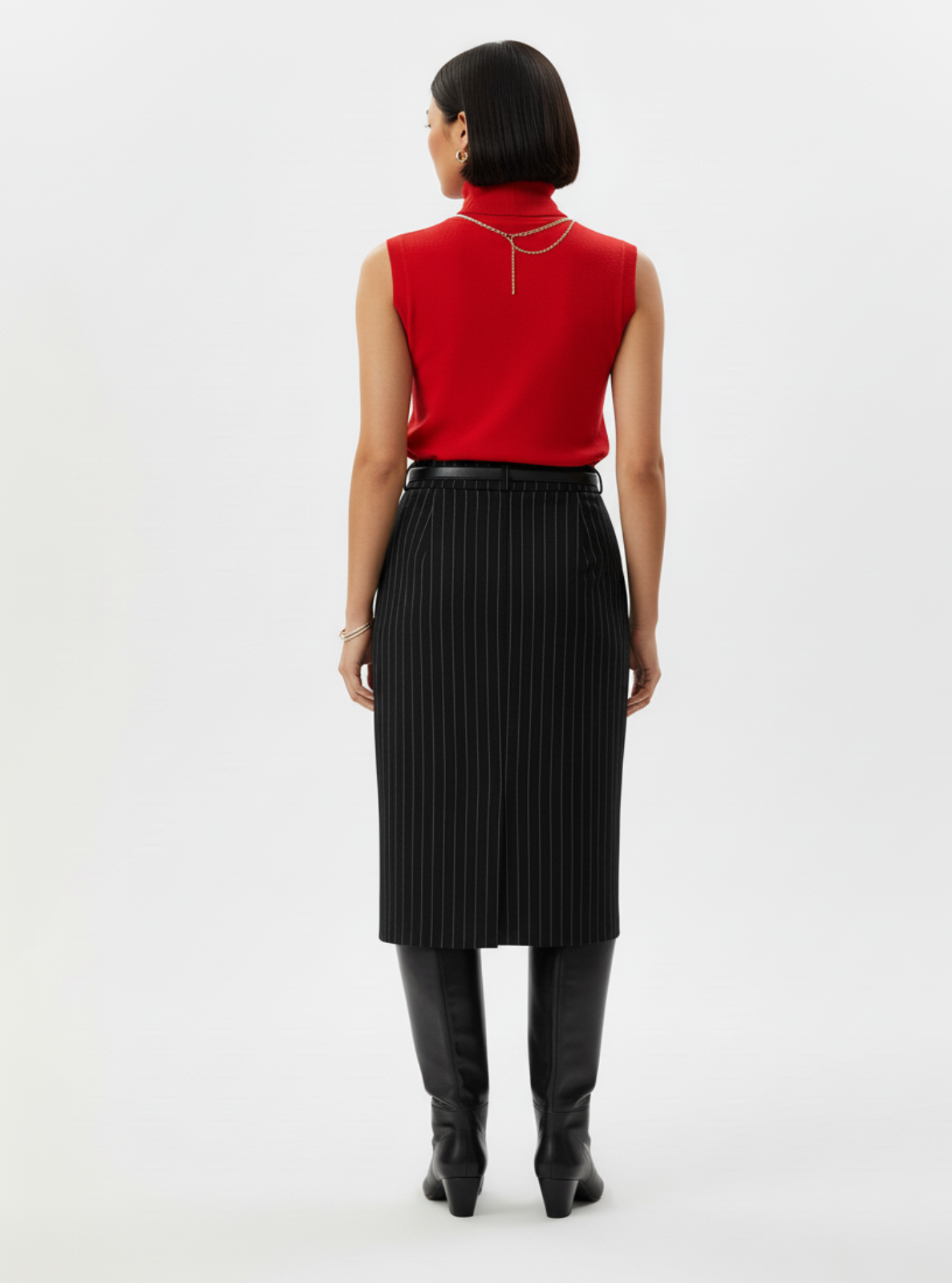 Person wearing a red sleeveless top and black skirt on a white background