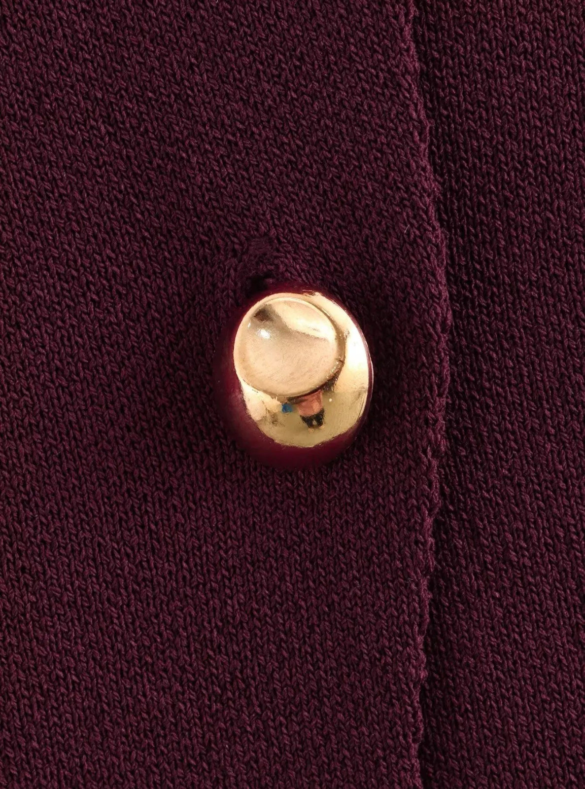 Close-up of a gold button on a burgundy fabric background