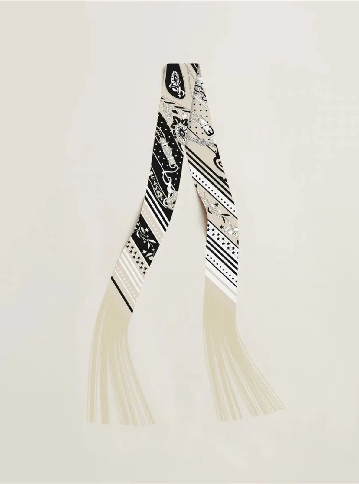 Black and white patterned scarf with tassels on a light gray background