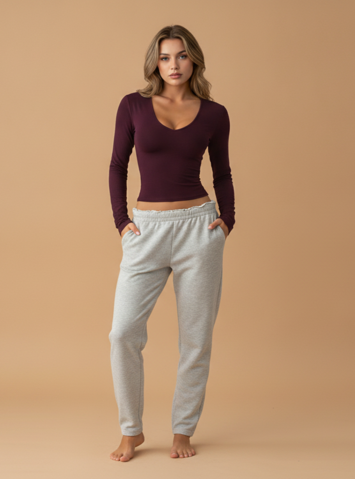 Woman wearing a purple long-sleeve top and gray sweatpants on a beige background
