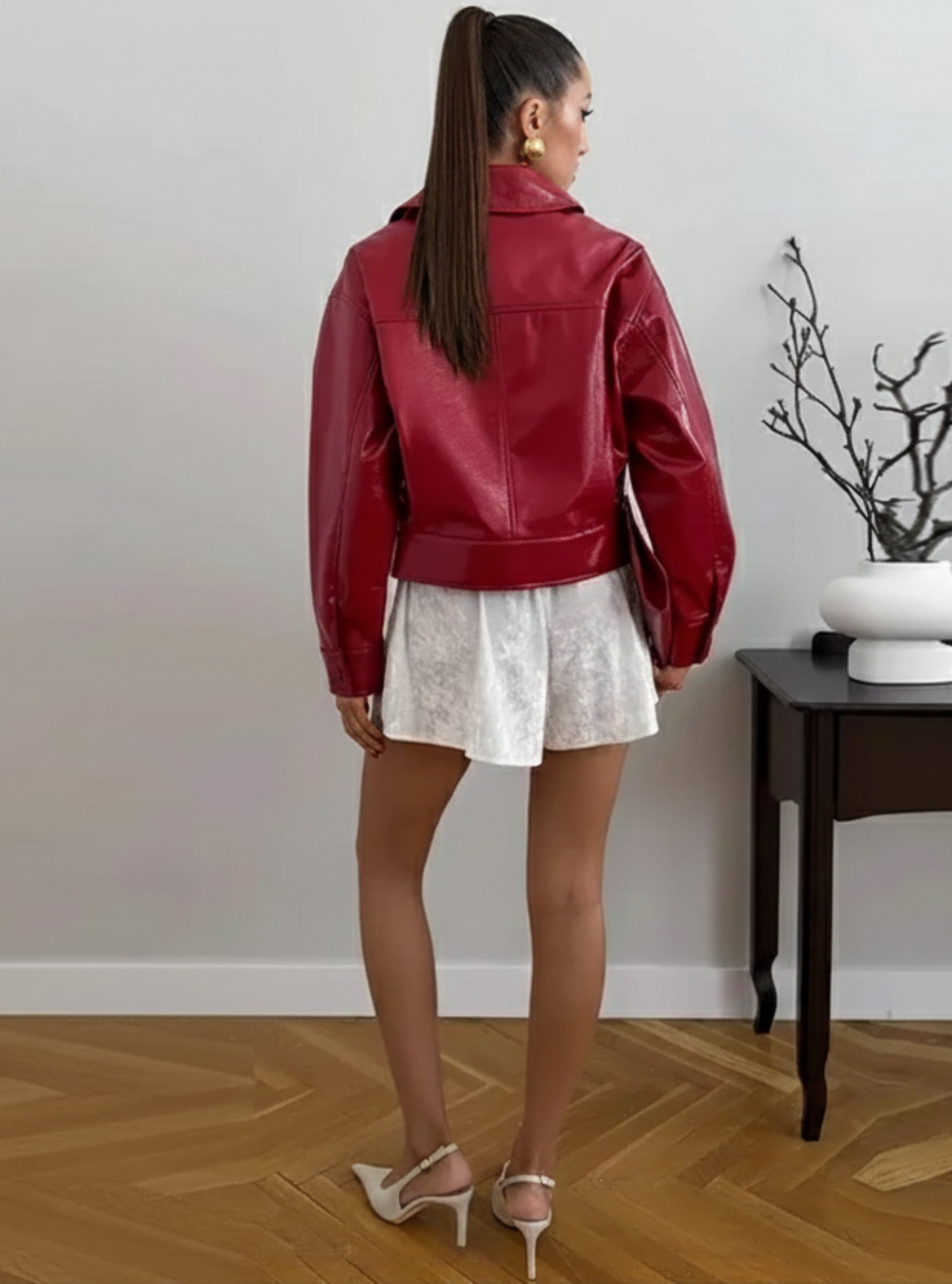 Woman wearing a red leather jacket in a minimalistic room.