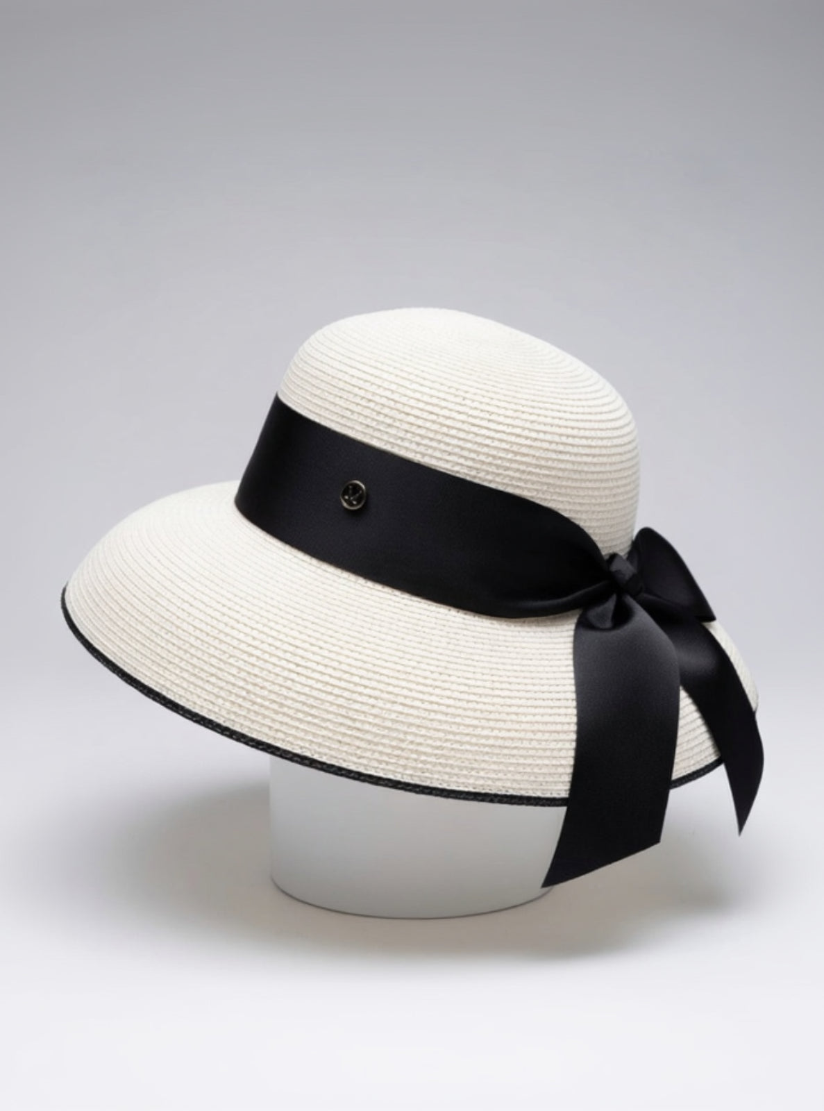 White straw hat with a black ribbon on a light gray background