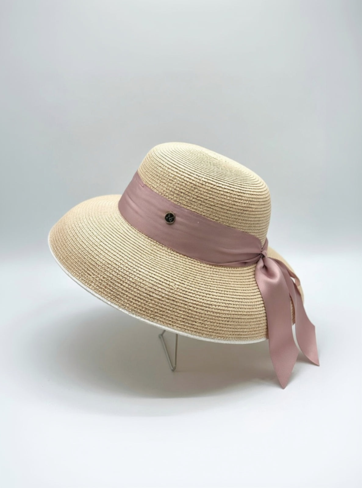Beige straw hat with a pink ribbon on a white background