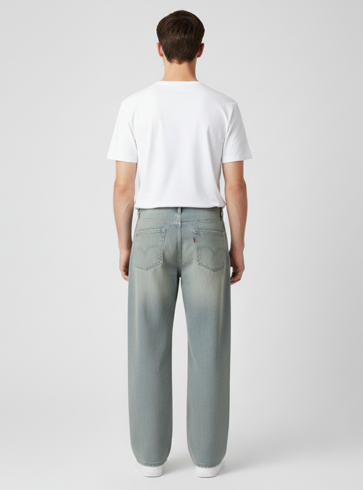 Person wearing light gray jeans and a white t-shirt on a plain background