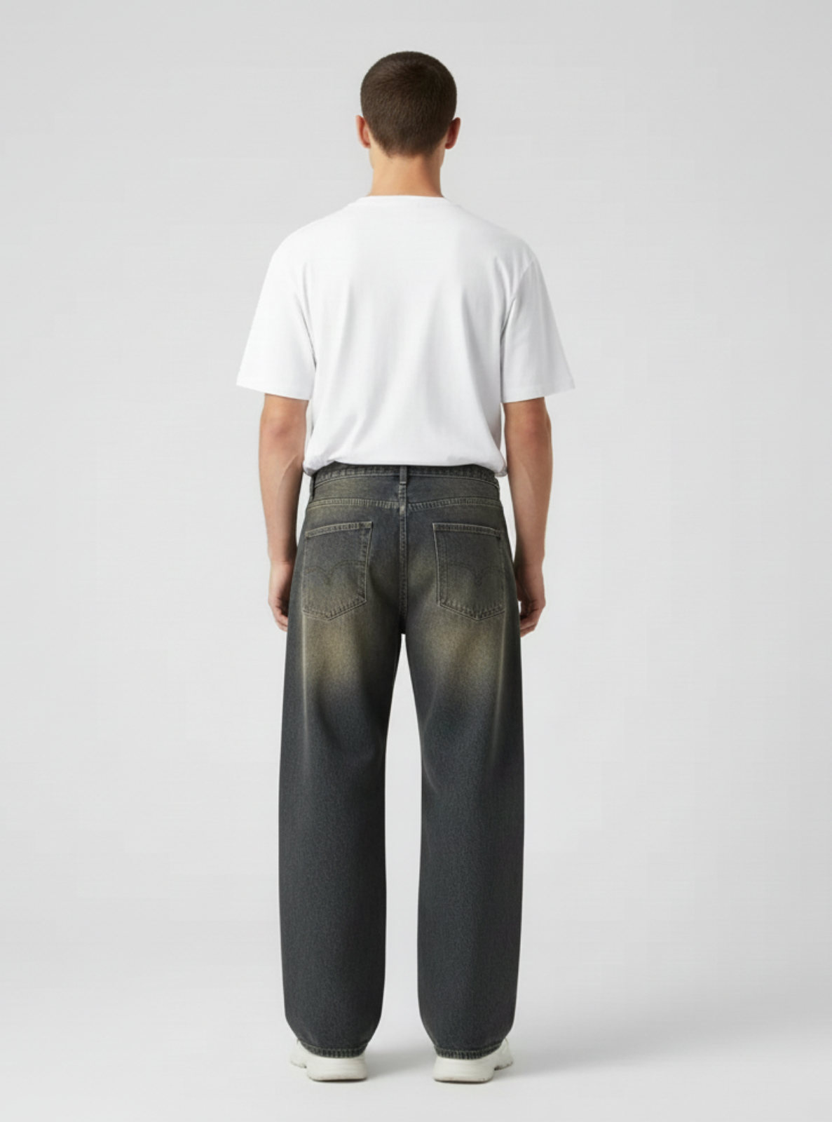 Person wearing a white t-shirt and dark jeans on a plain background