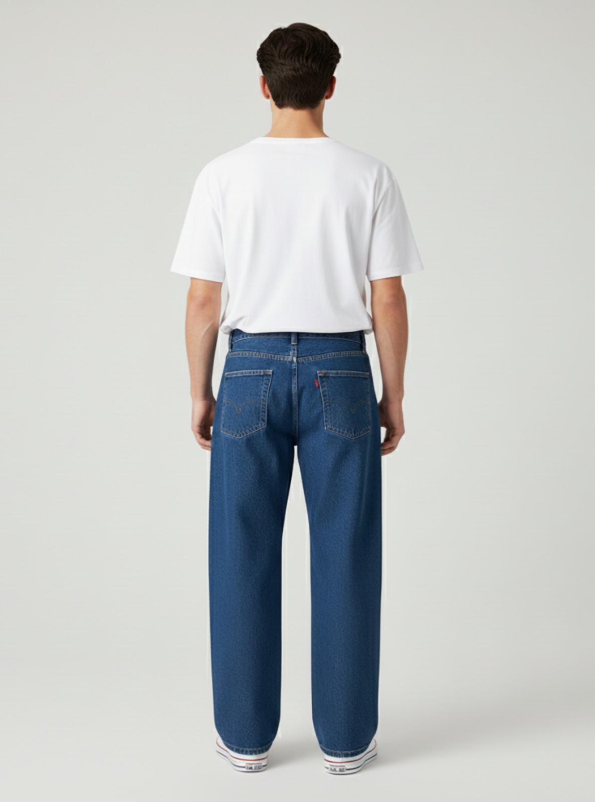 Person wearing blue jeans and a white t-shirt on a plain background