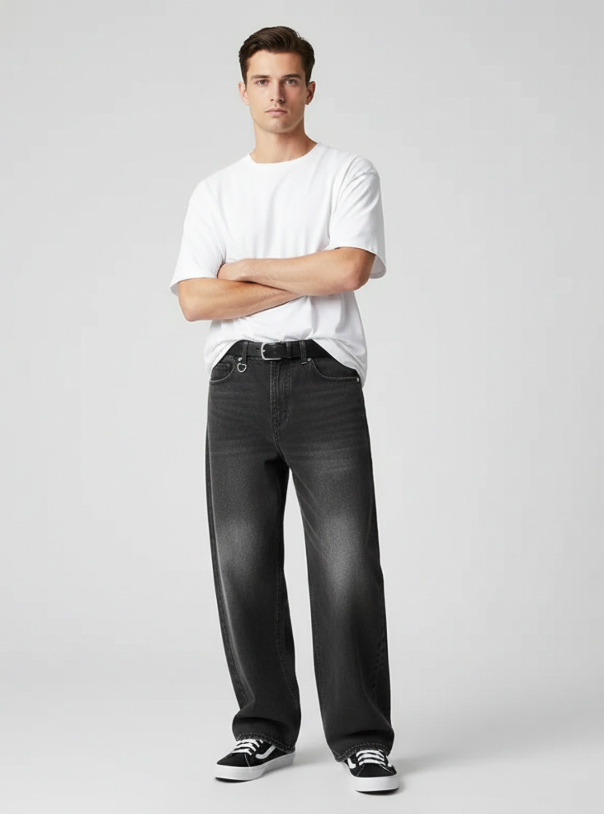 Man wearing a white t-shirt and black jeans on a gray background