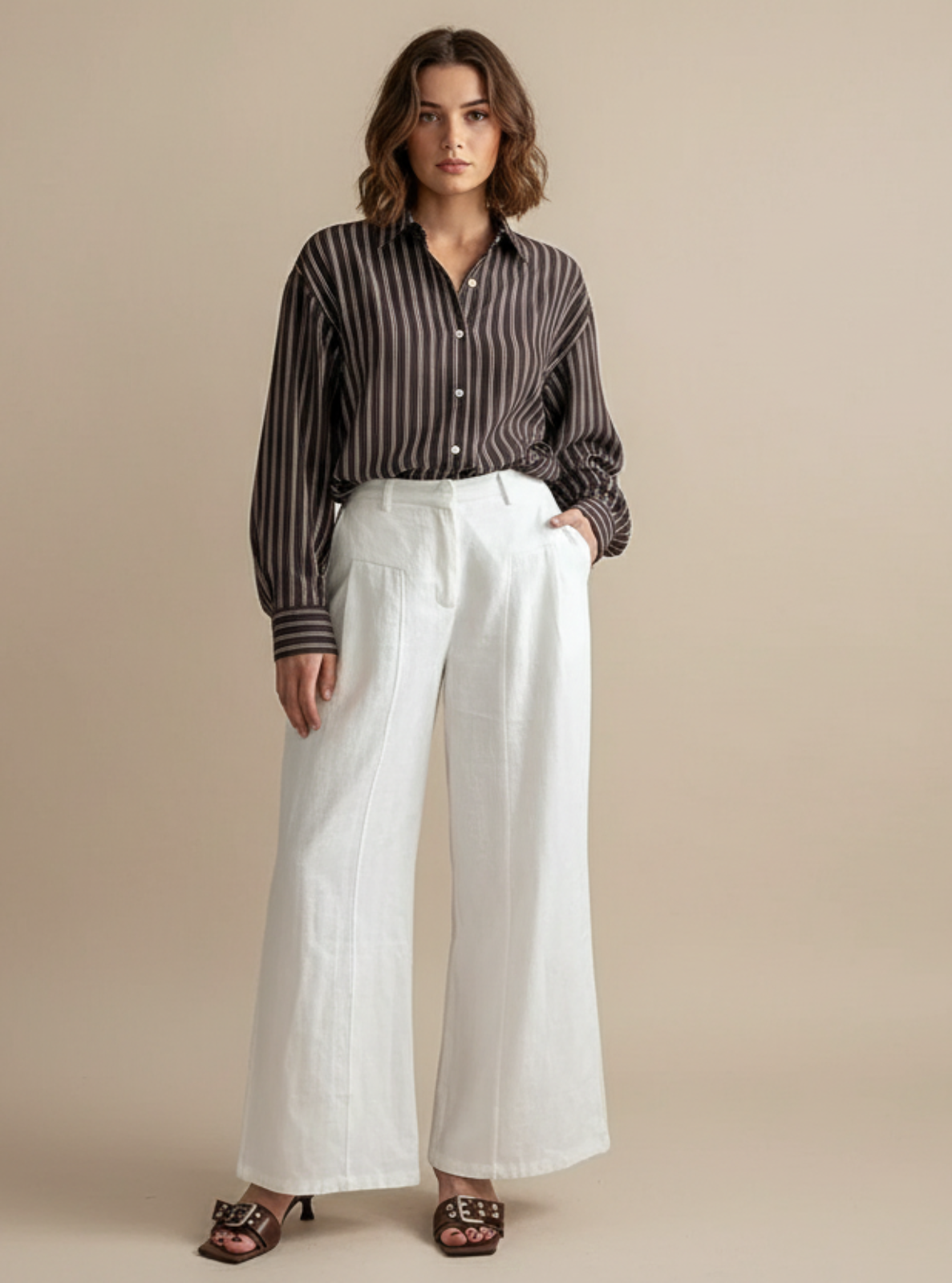 Woman wearing a striped shirt and white pants on a beige background