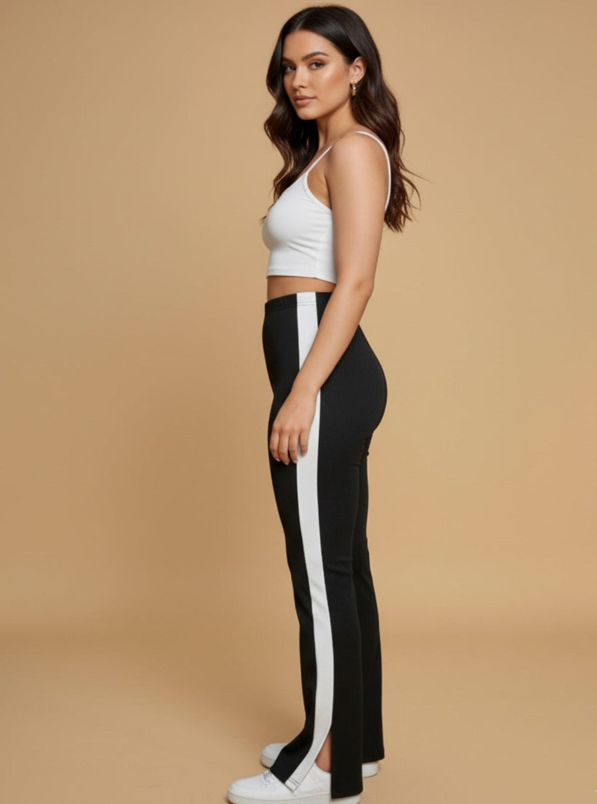 Woman wearing a white crop top and black pants with a white stripe on a beige background