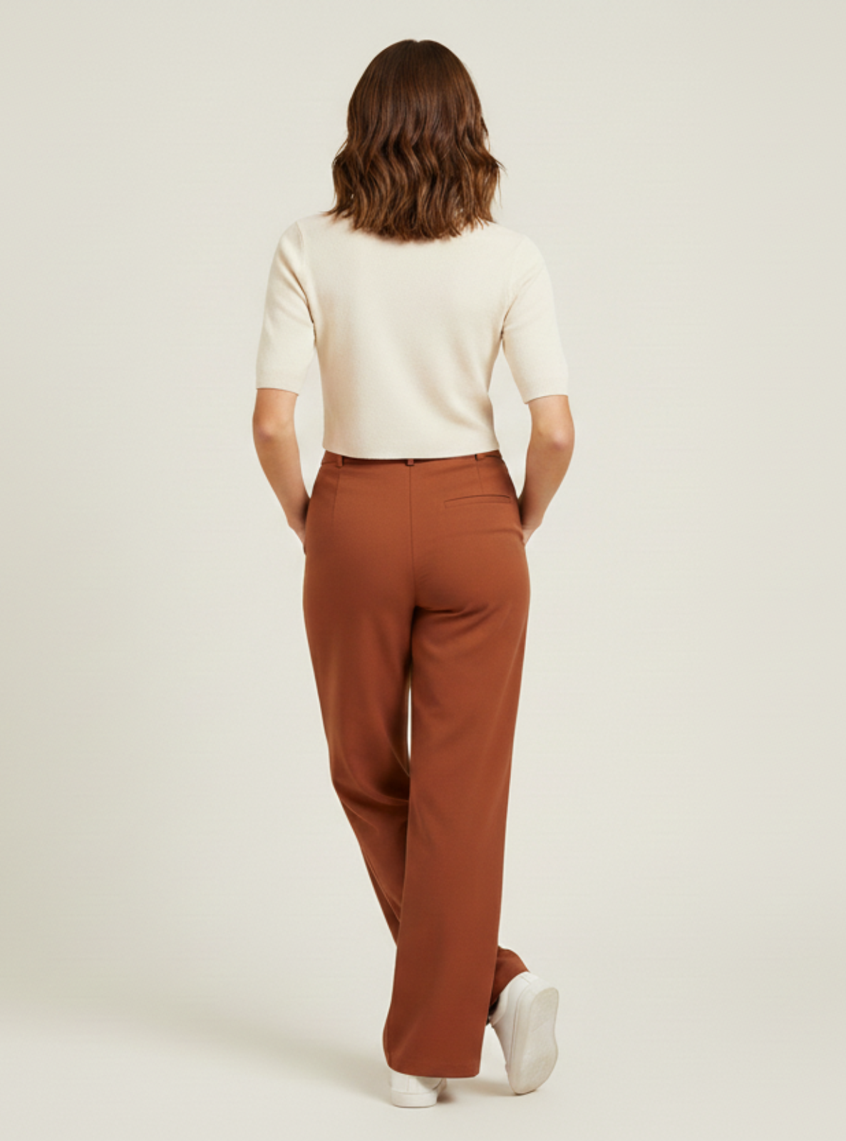 Person wearing a white shirt and brown pants on a plain background