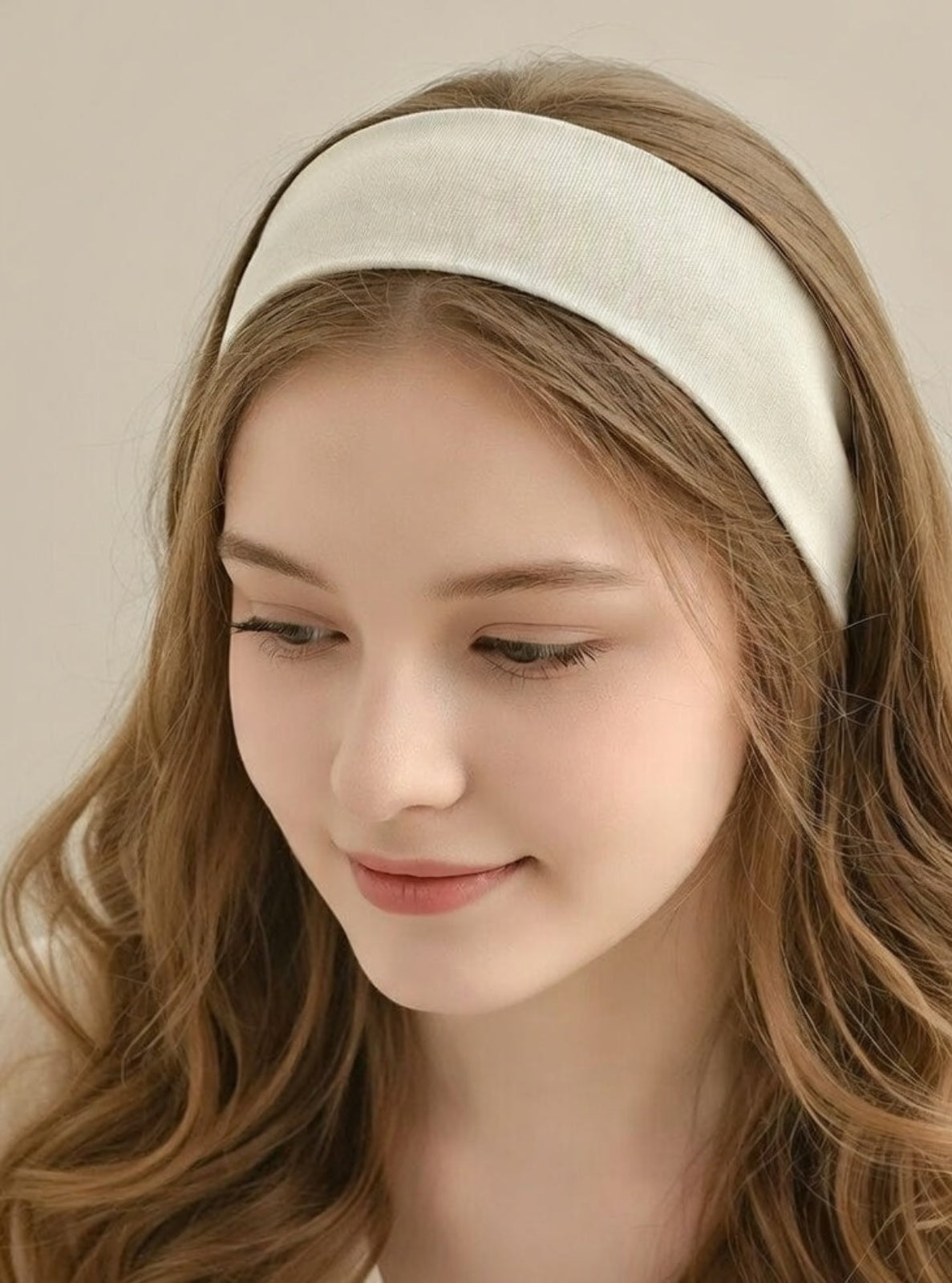 Woman wearing a beige headband against a neutral background