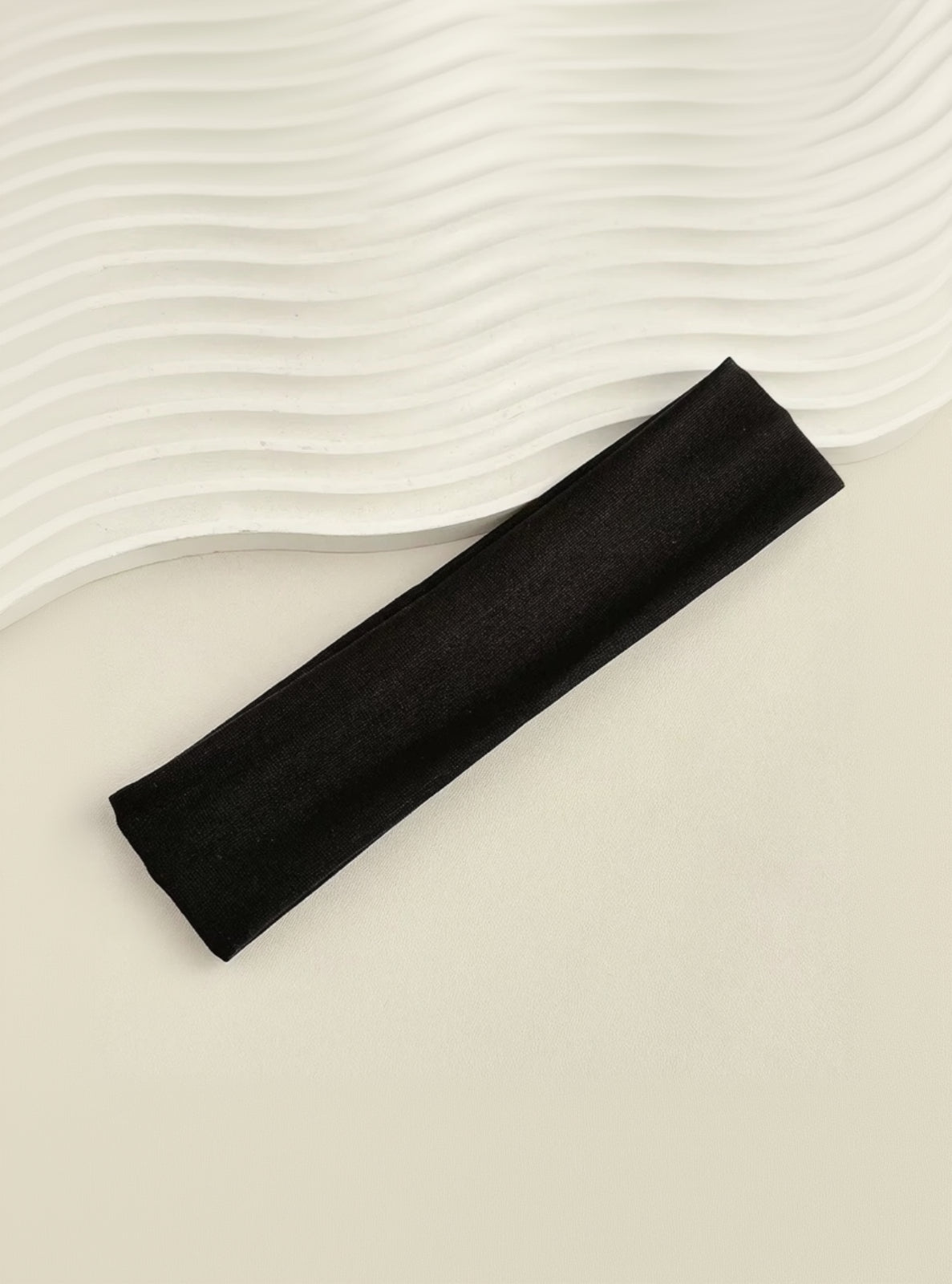 Black headband on a textured beige surface