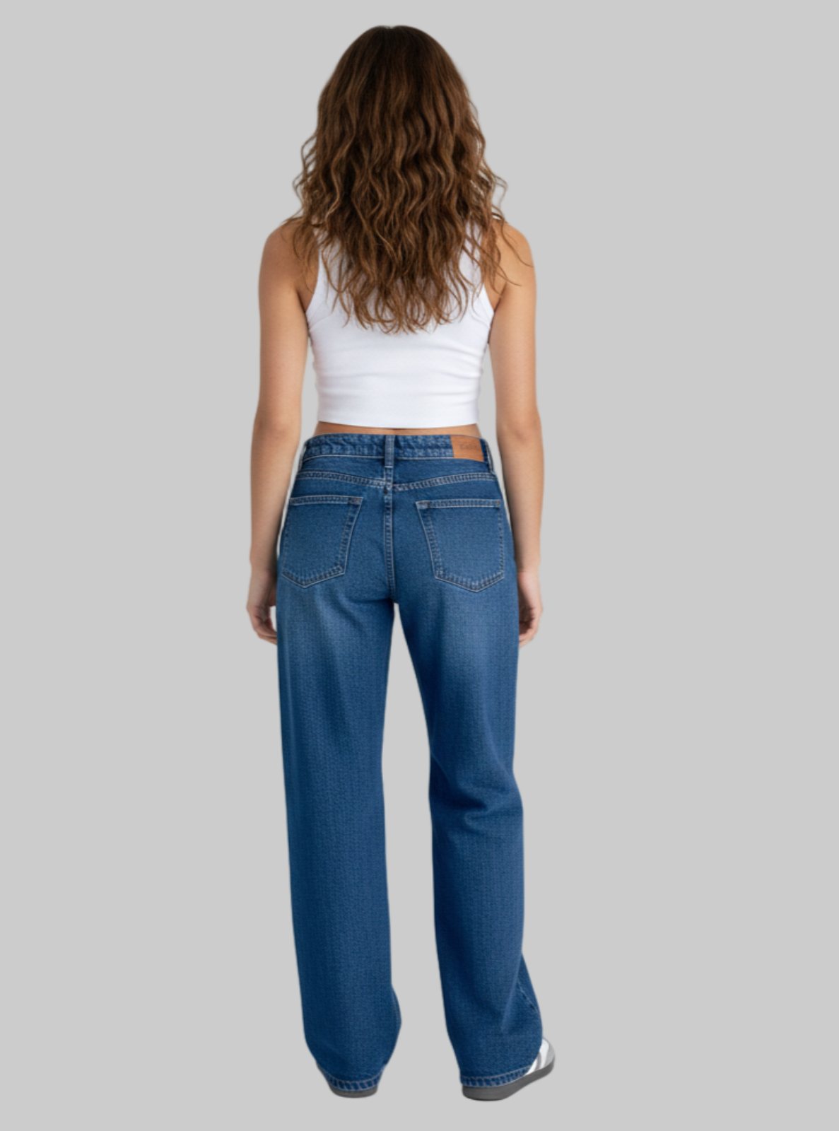 Person wearing blue jeans and a white tank top on a white background