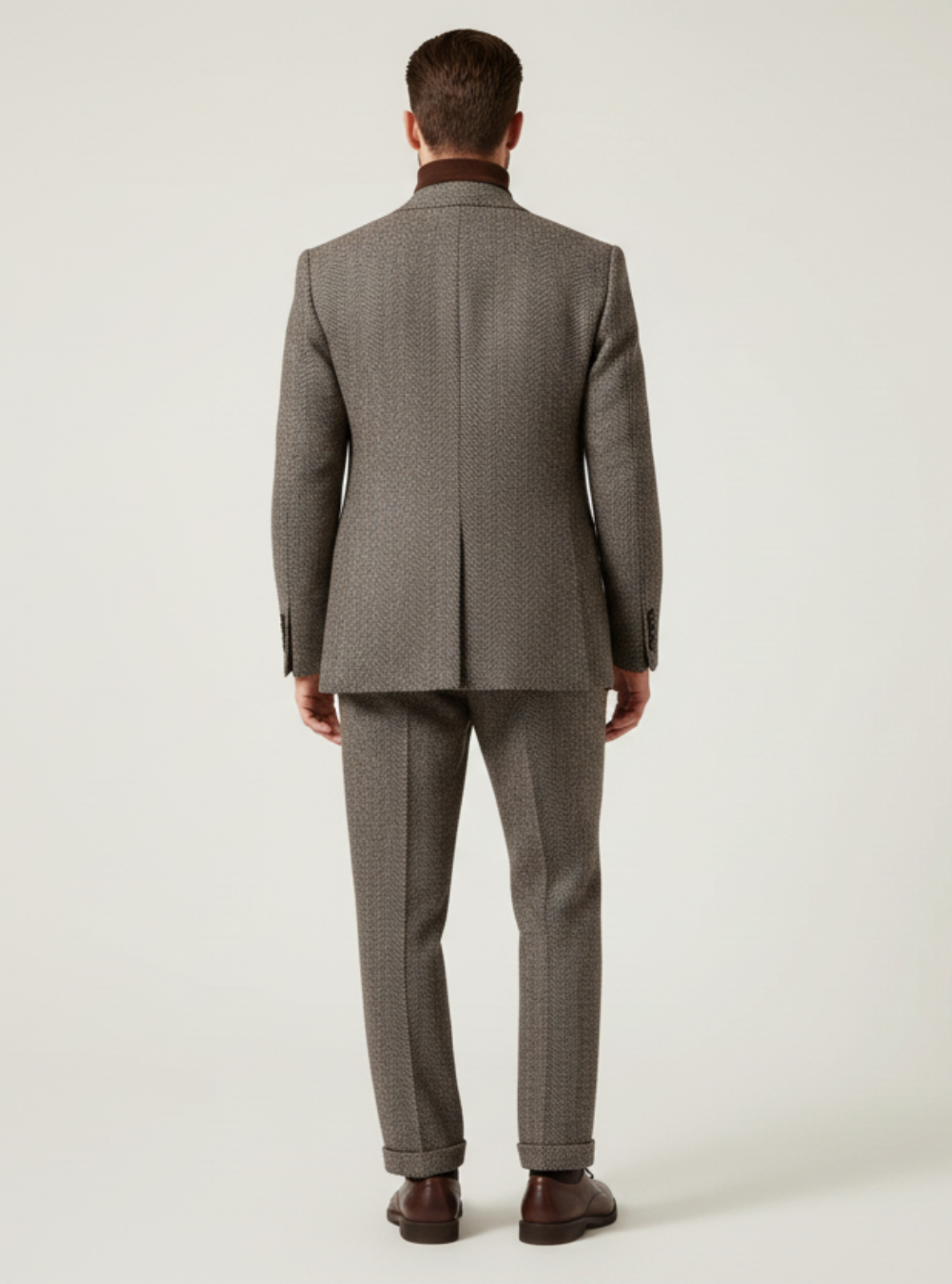 Man wearing a gray suit standing against a white background