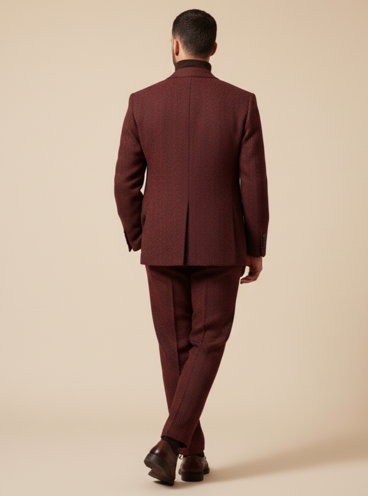 Man wearing a burgundy suit standing against a beige background