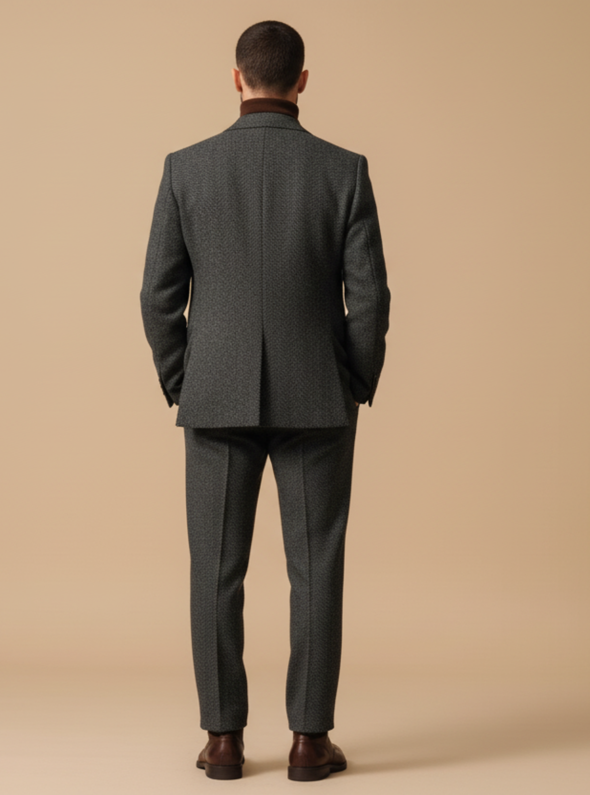 Man wearing a gray suit standing against a beige background