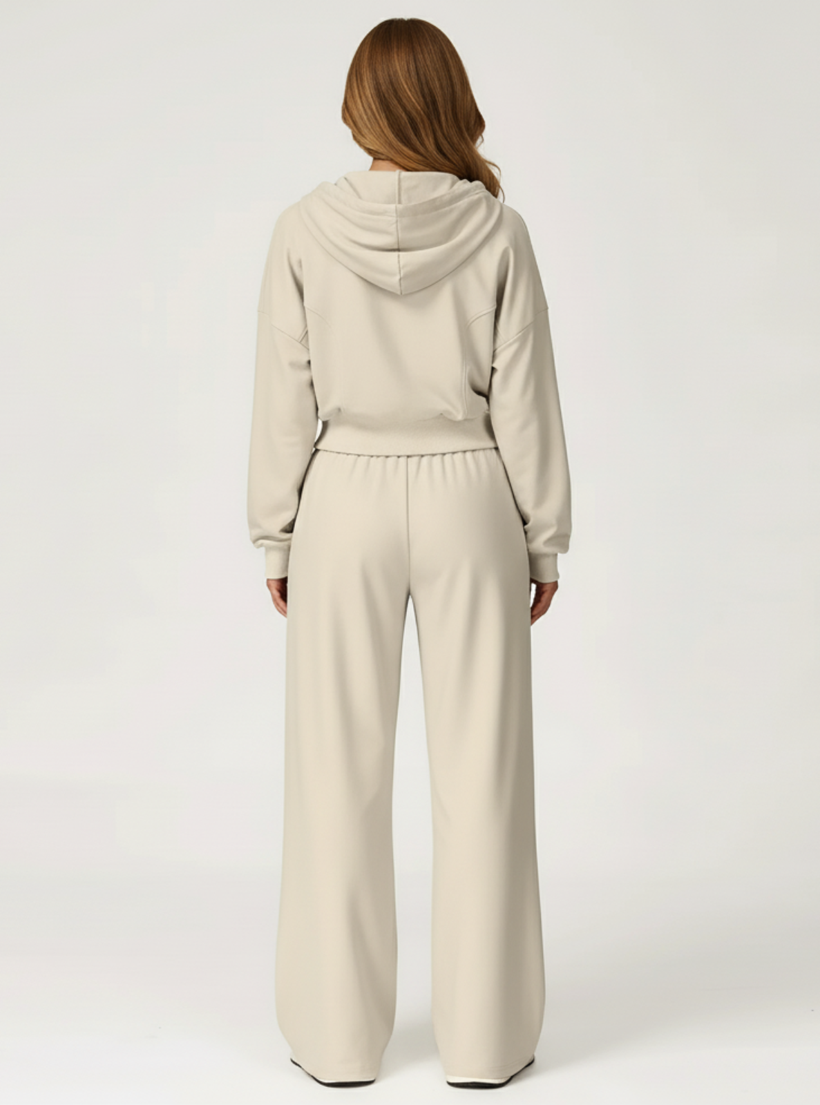 Person wearing a beige hoodie and pants on a white background