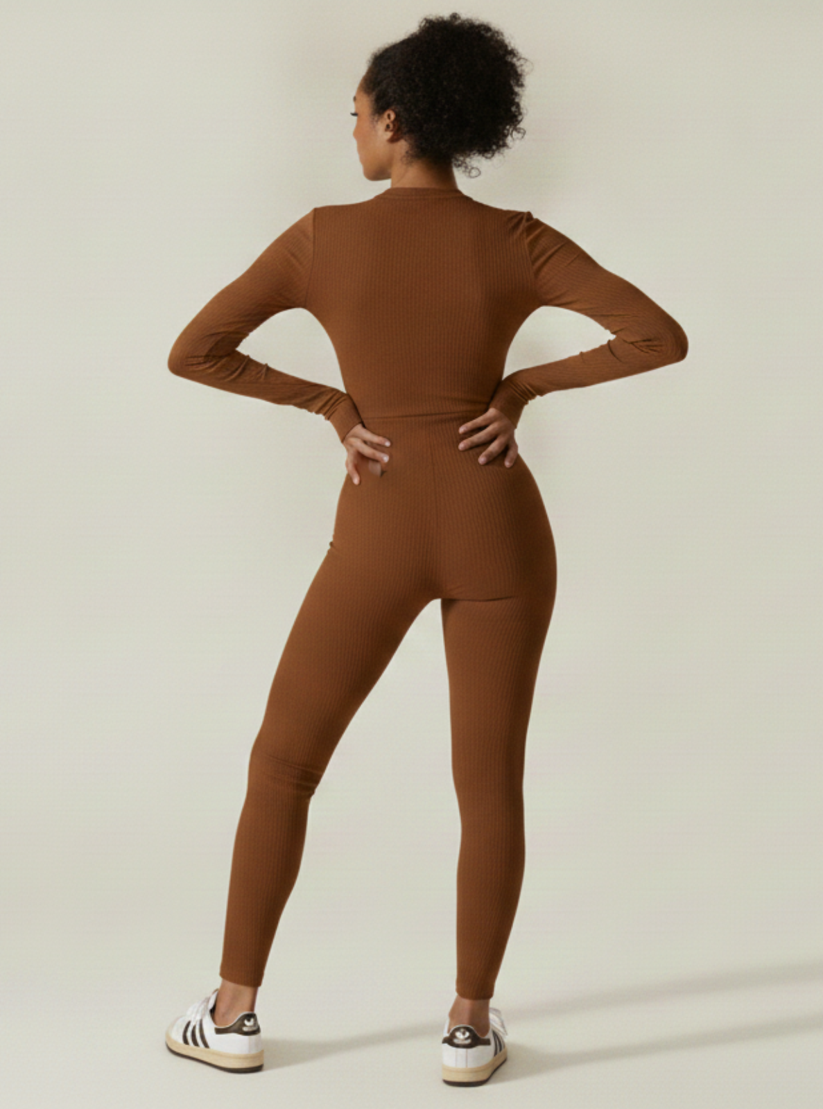 Person wearing a brown jumpsuit on a plain background
