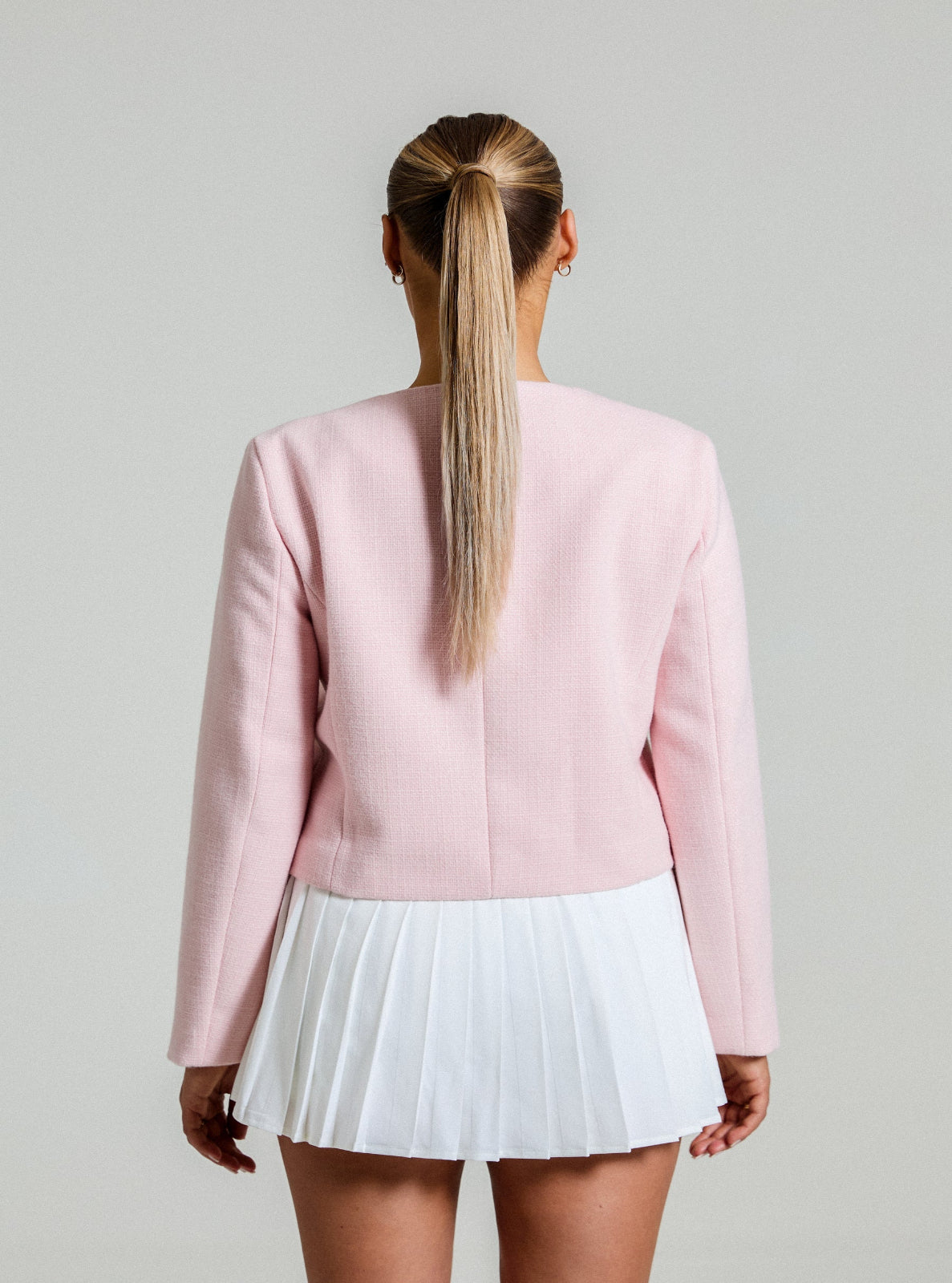 model facing background wearing a pink textured Jacket 