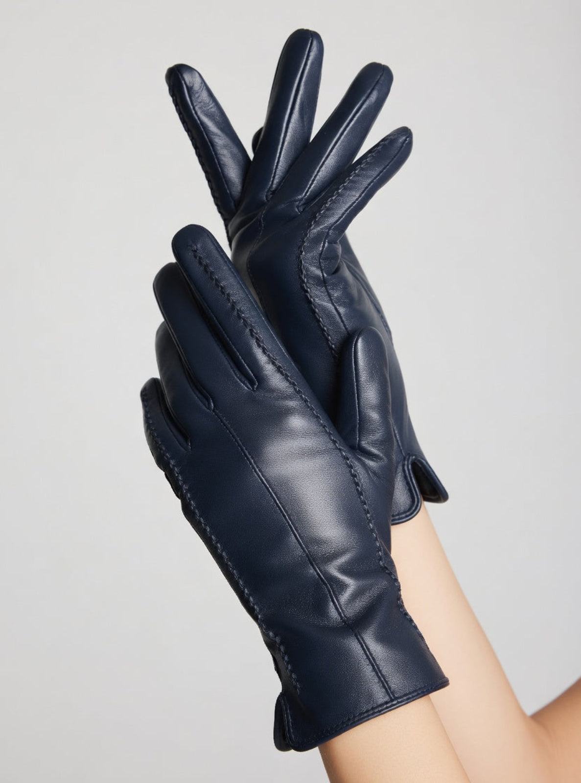 Pair of dark blue leather gloves on a light gray background