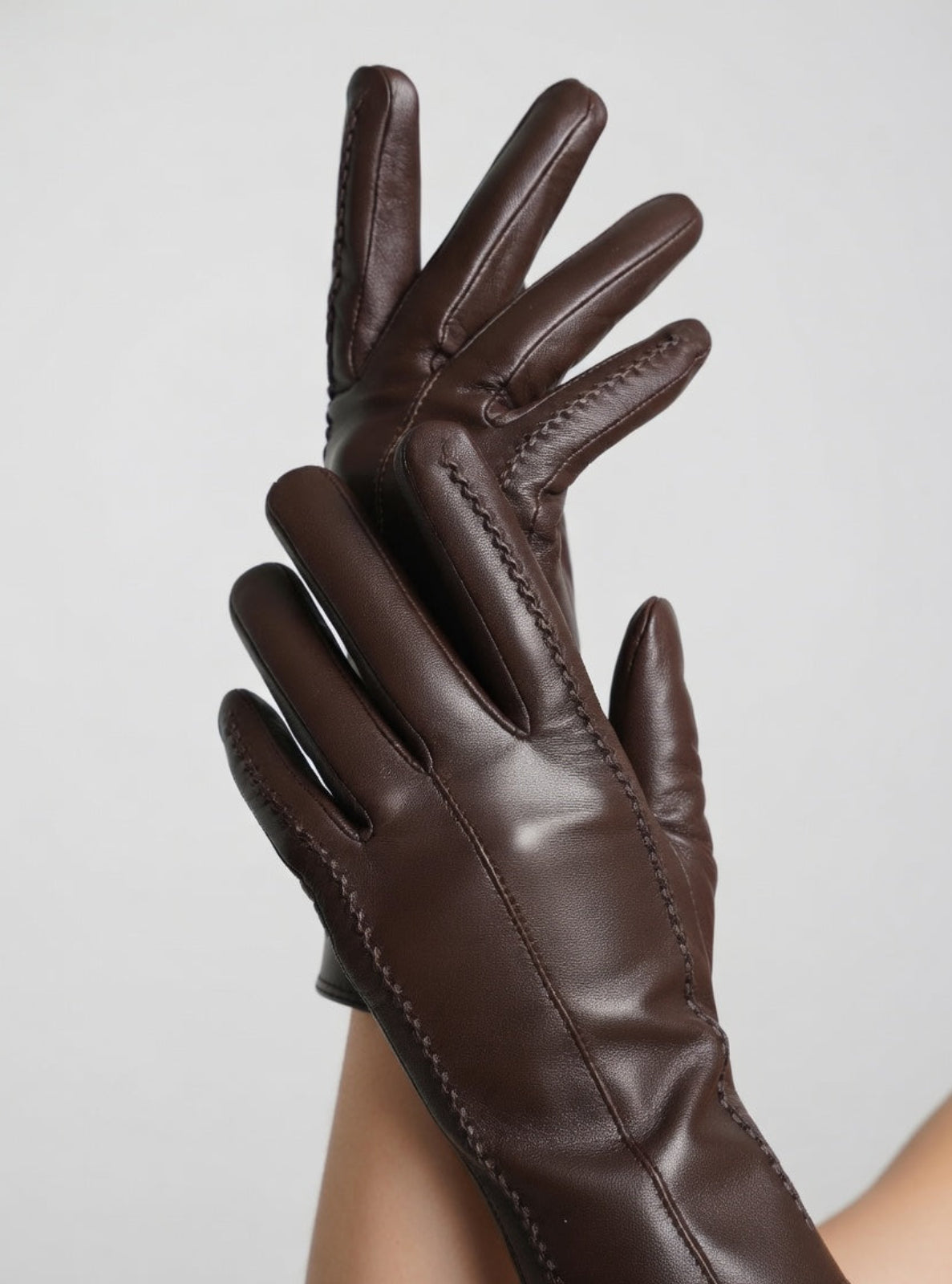 Pair of brown leather gloves on a light gray background