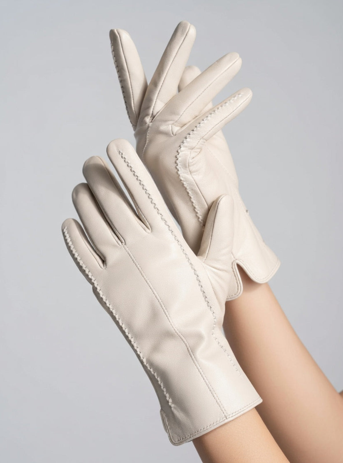 Beige leather gloves on a gray background
