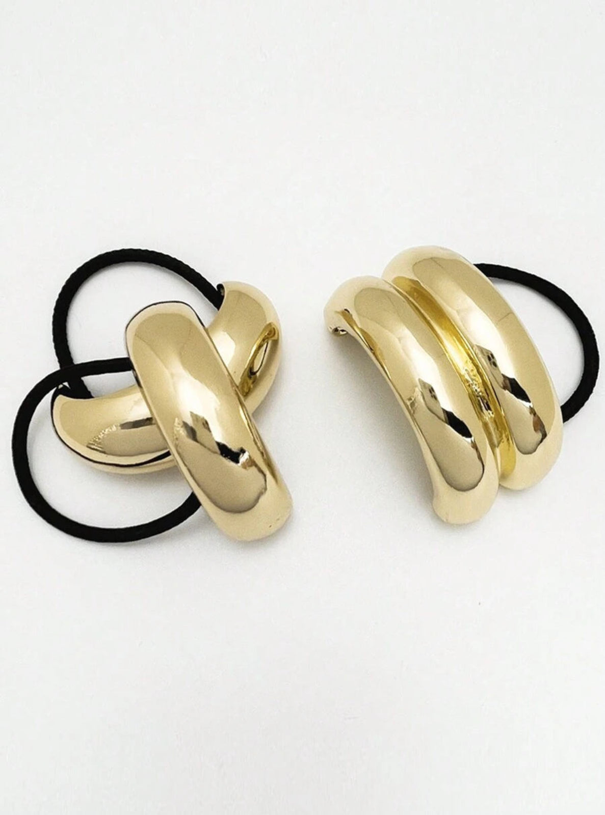 Gold hair ties with black elastic bands on a white background