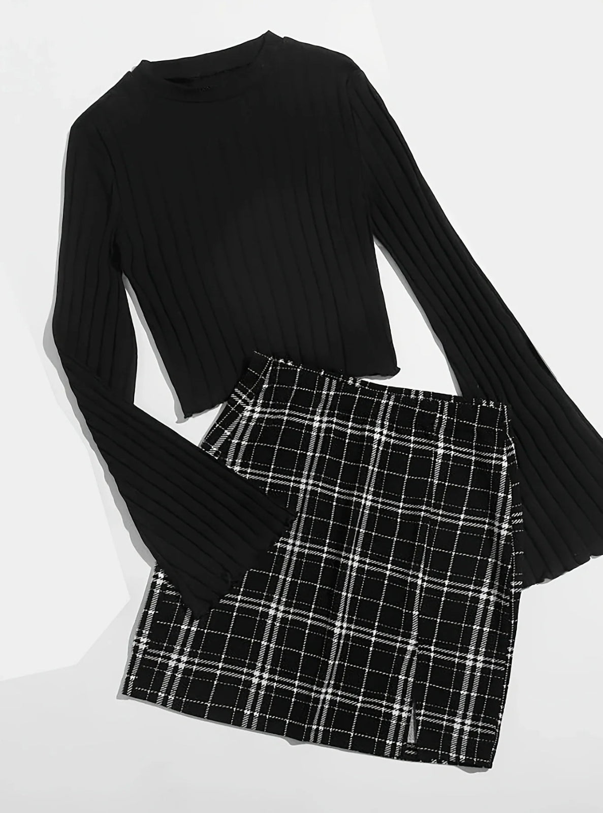Black ribbed long-sleeve top and plaid skirt on a white background
