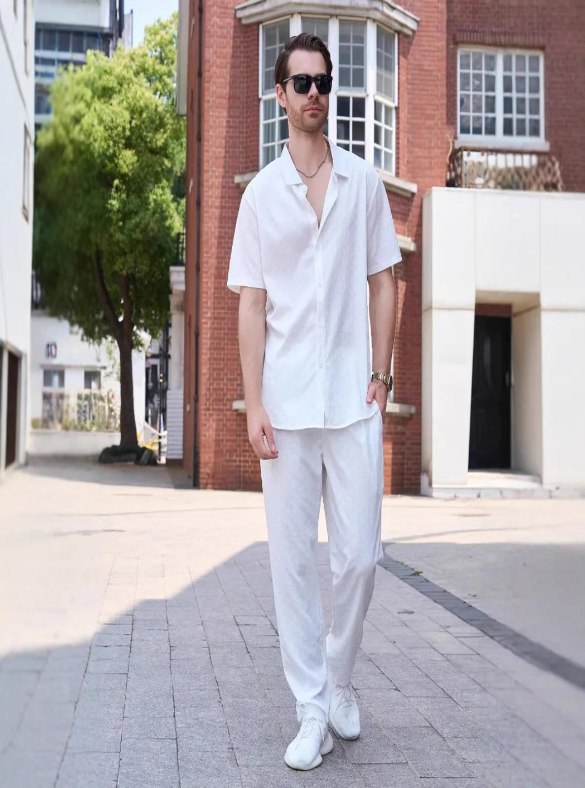 Man wearing a white outfit standing on a street with a building in the background