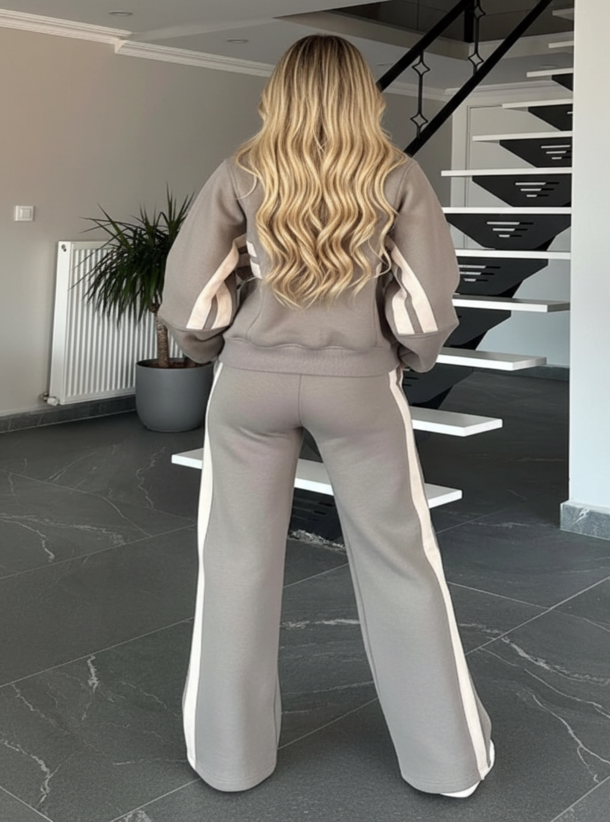 Person wearing a gray outfit with white stripes in a modern interior setting.