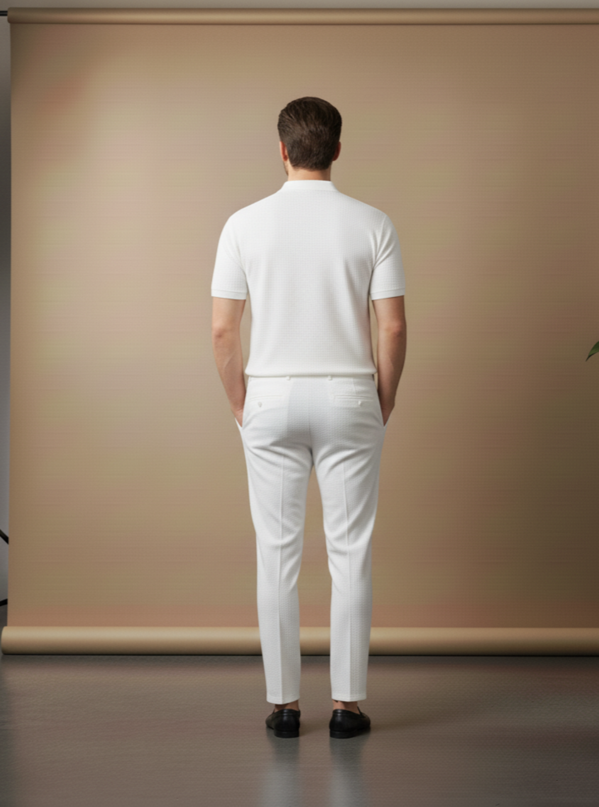 Man wearing a white outfit standing in front of a beige backdrop