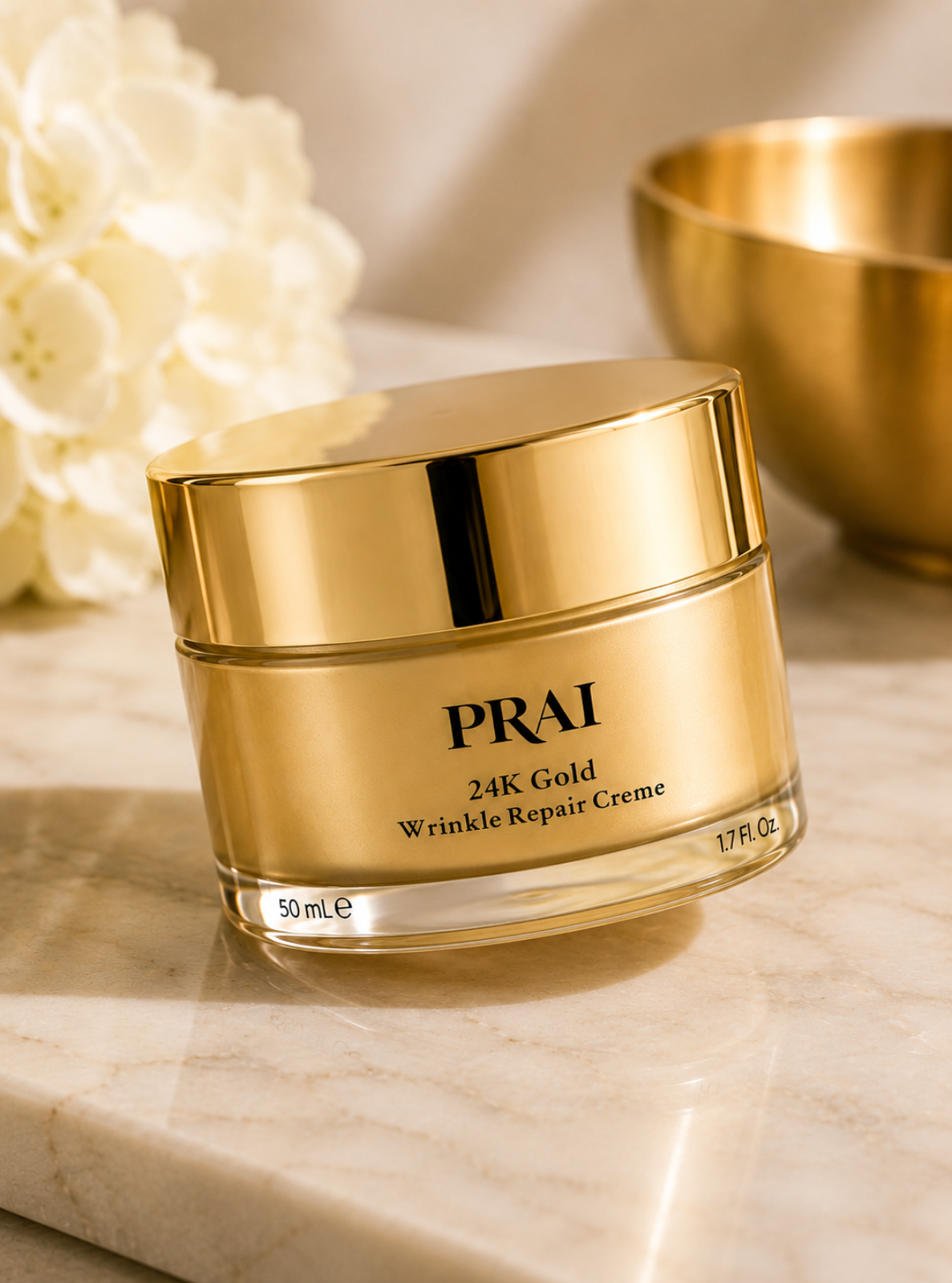 A gold cosmetic jar labeled PRAI 24K Gold Wrinkle Repair Creme, placed on a light marble surface with soft-focus white flowers and a gold bowl in the background.