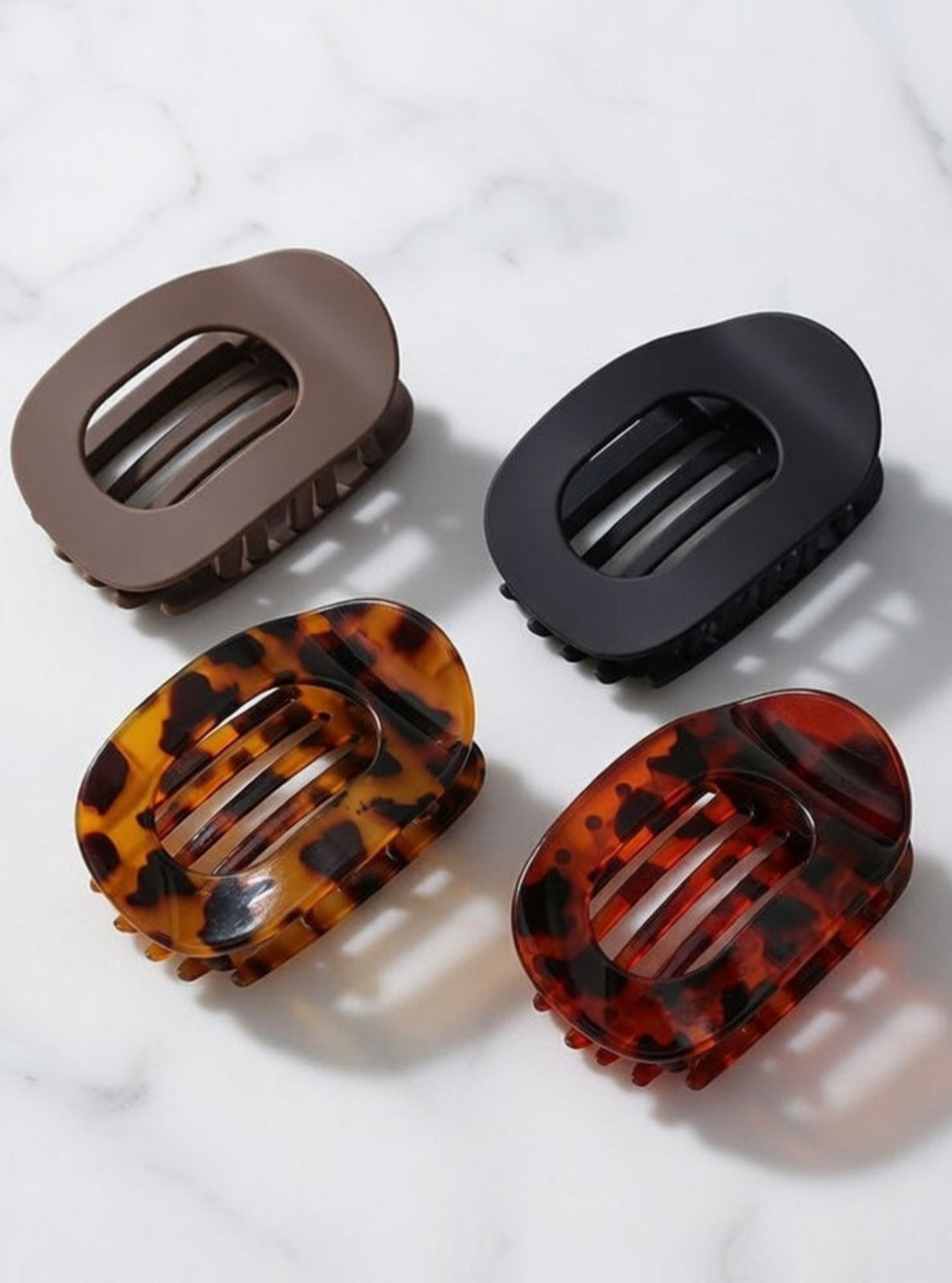 Four hair clips in different designs on a marble surface