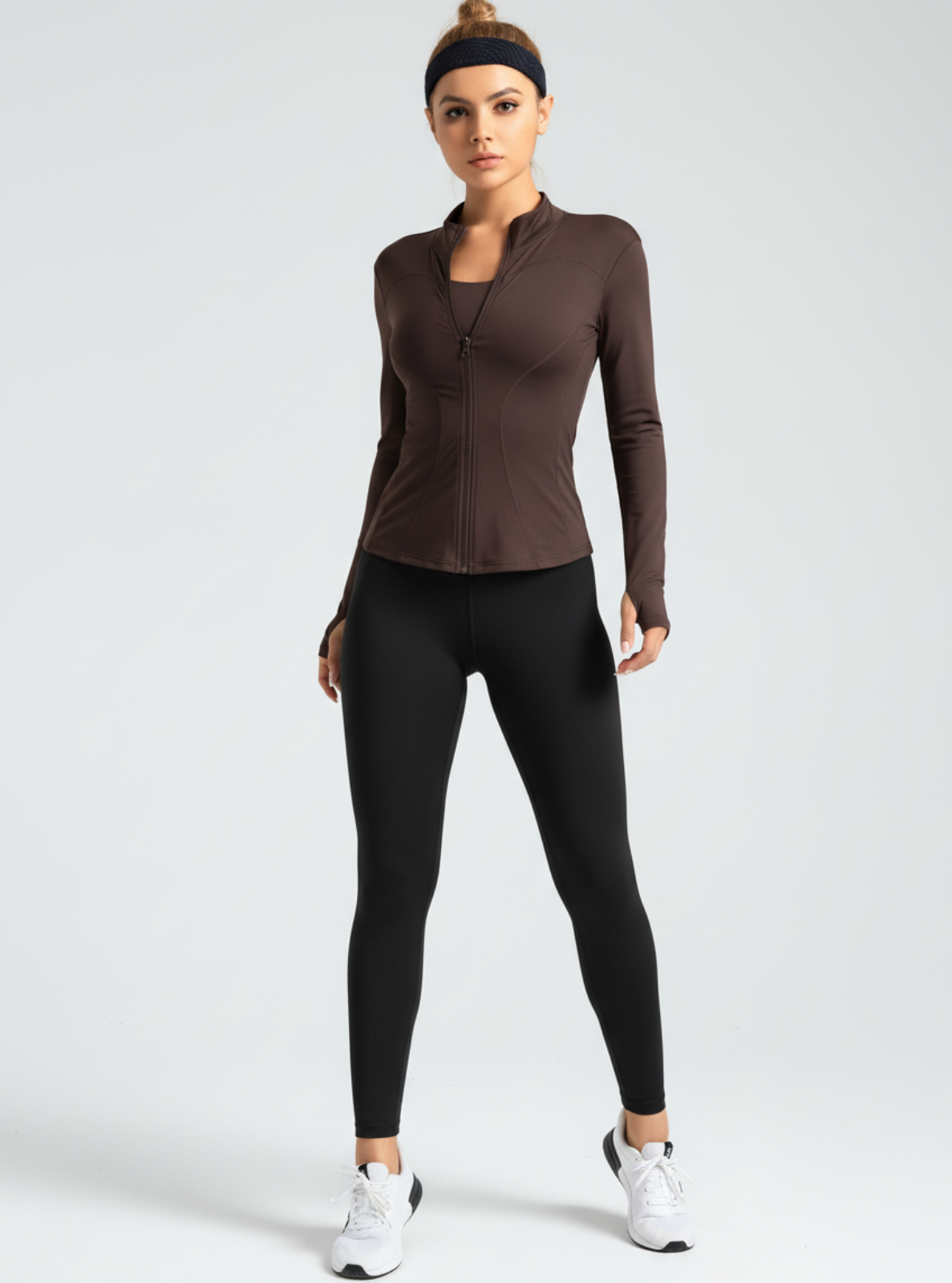 Woman wearing a brown long-sleeve athletic top and black leggings on a white background