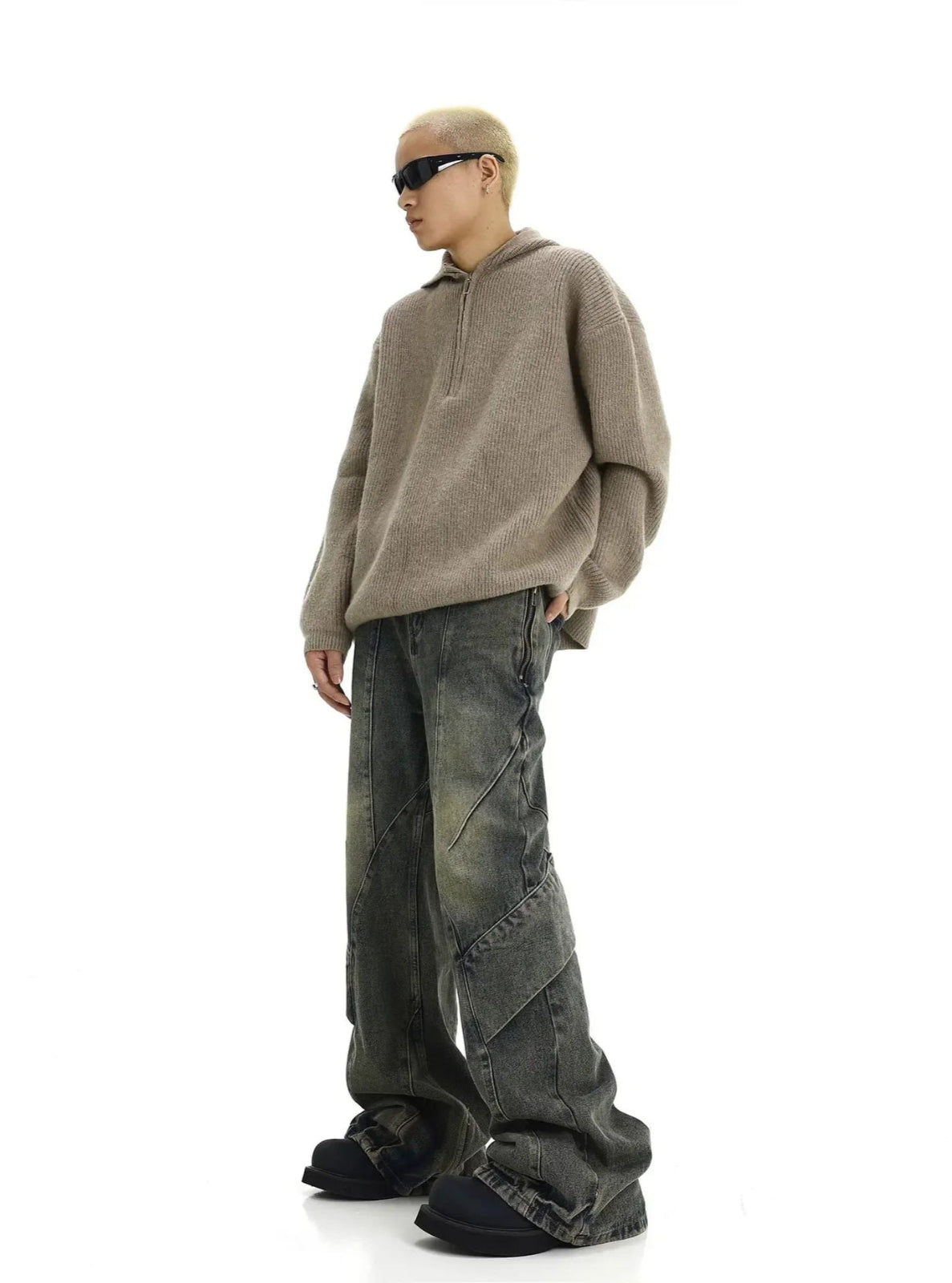 Person wearing a beige sweater and dark pants on a white background