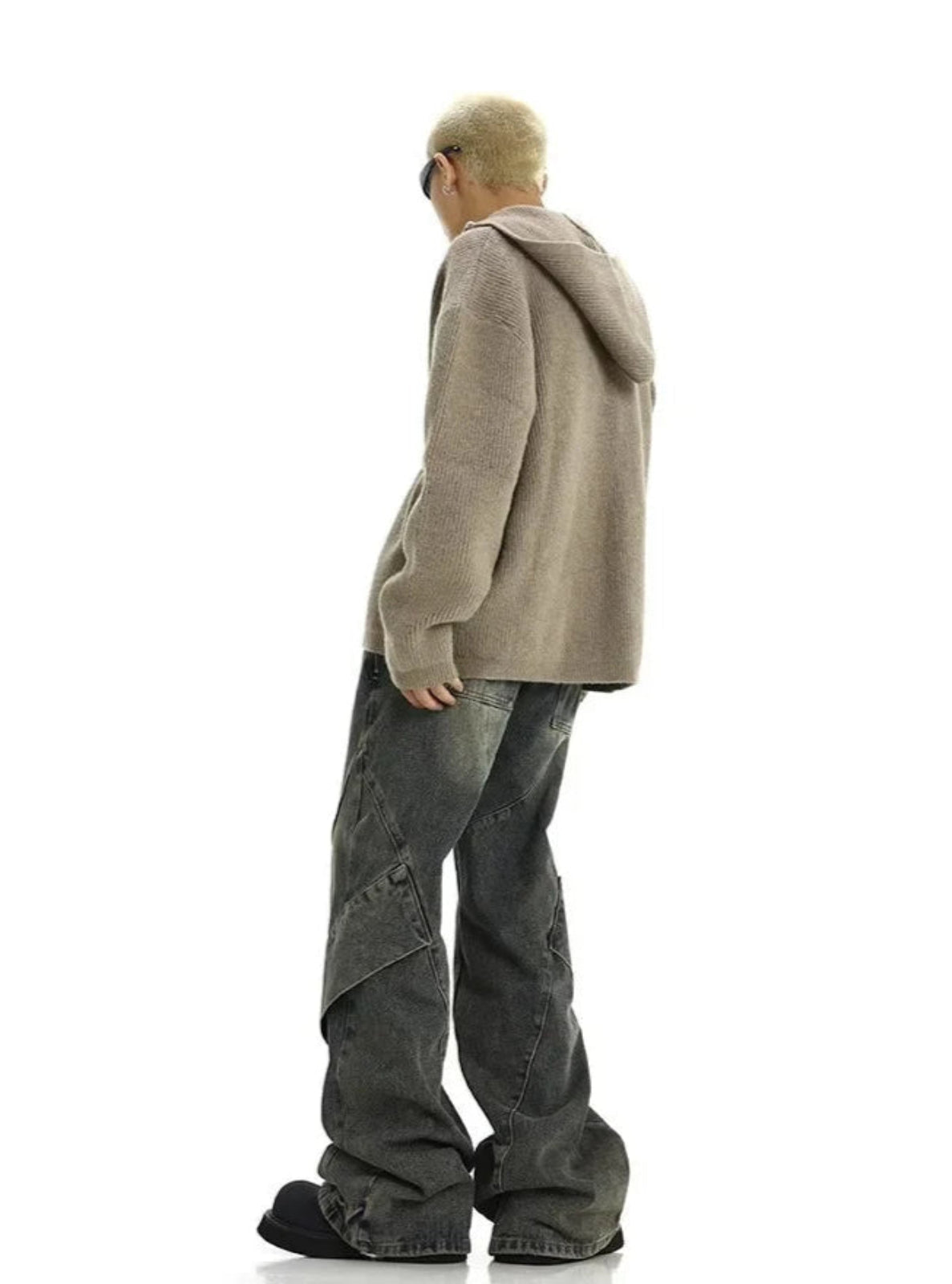 Person wearing a beige hoodie and gray pants on a white background