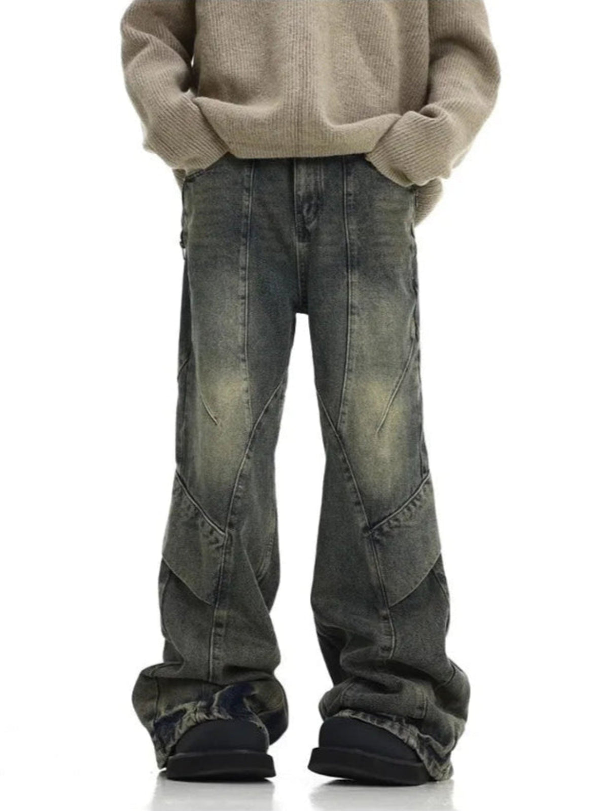 Person wearing a beige sweater and distressed jeans on a white background