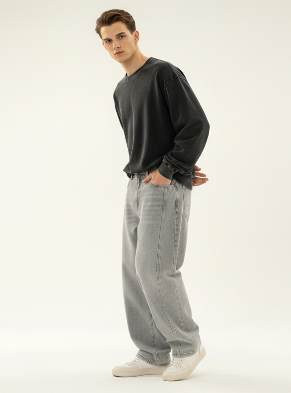 Man wearing a dark sweater and light gray pants on a white background