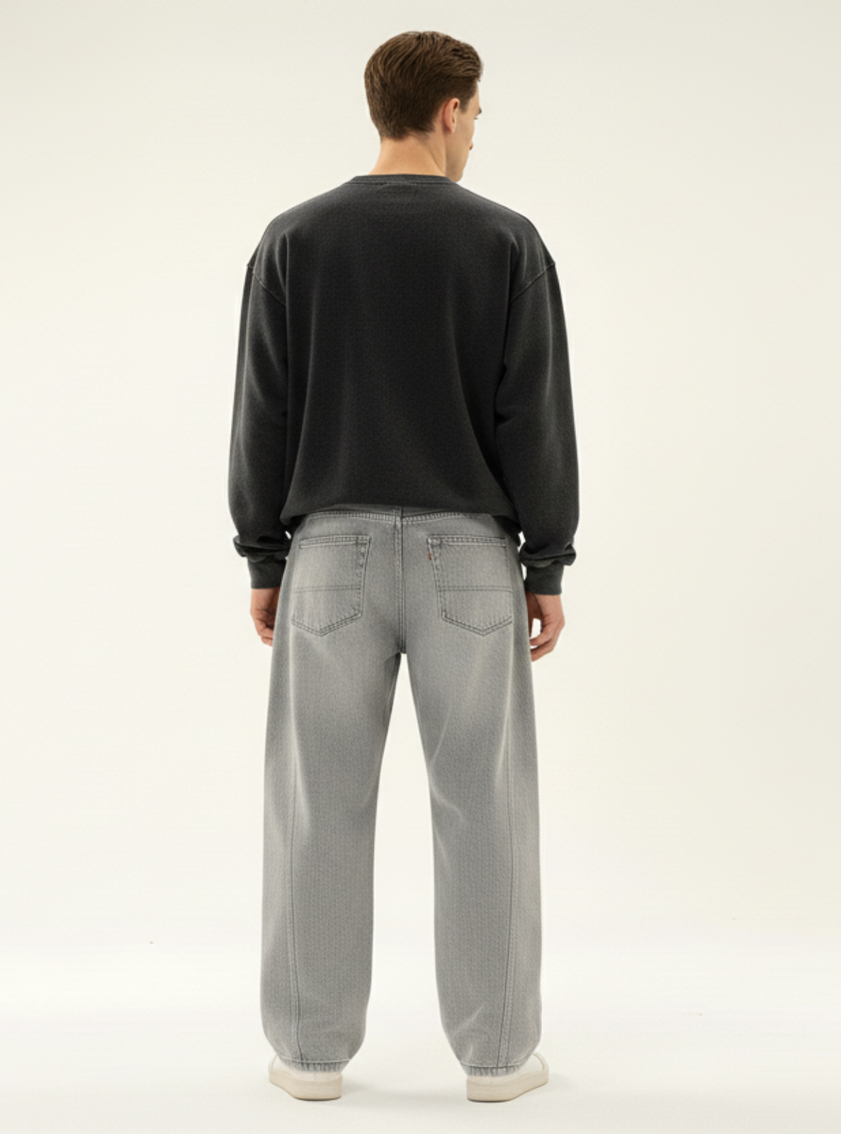 Person wearing a black sweater and gray pants on a white background