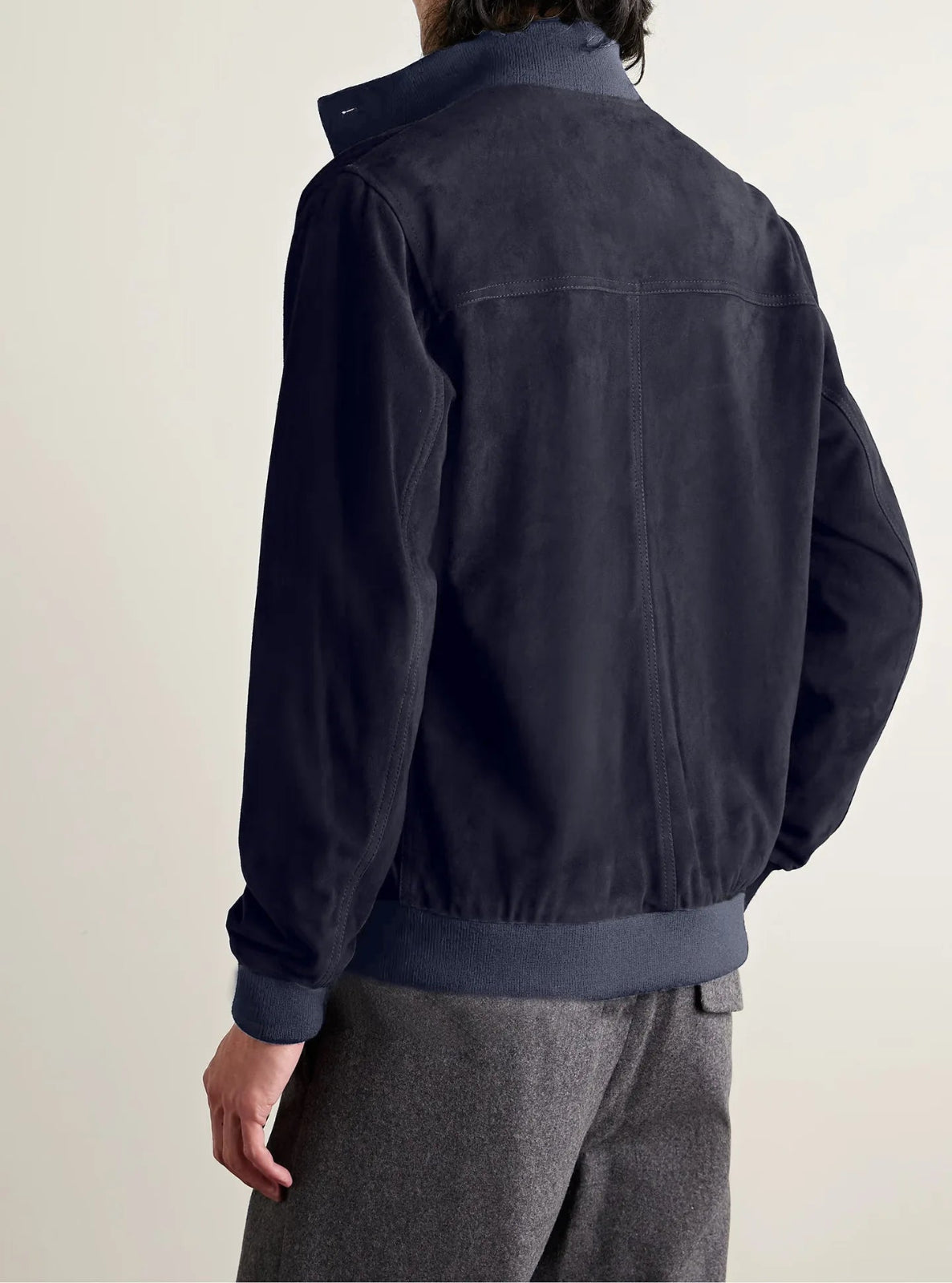 Person wearing a dark blue jacket on a plain background