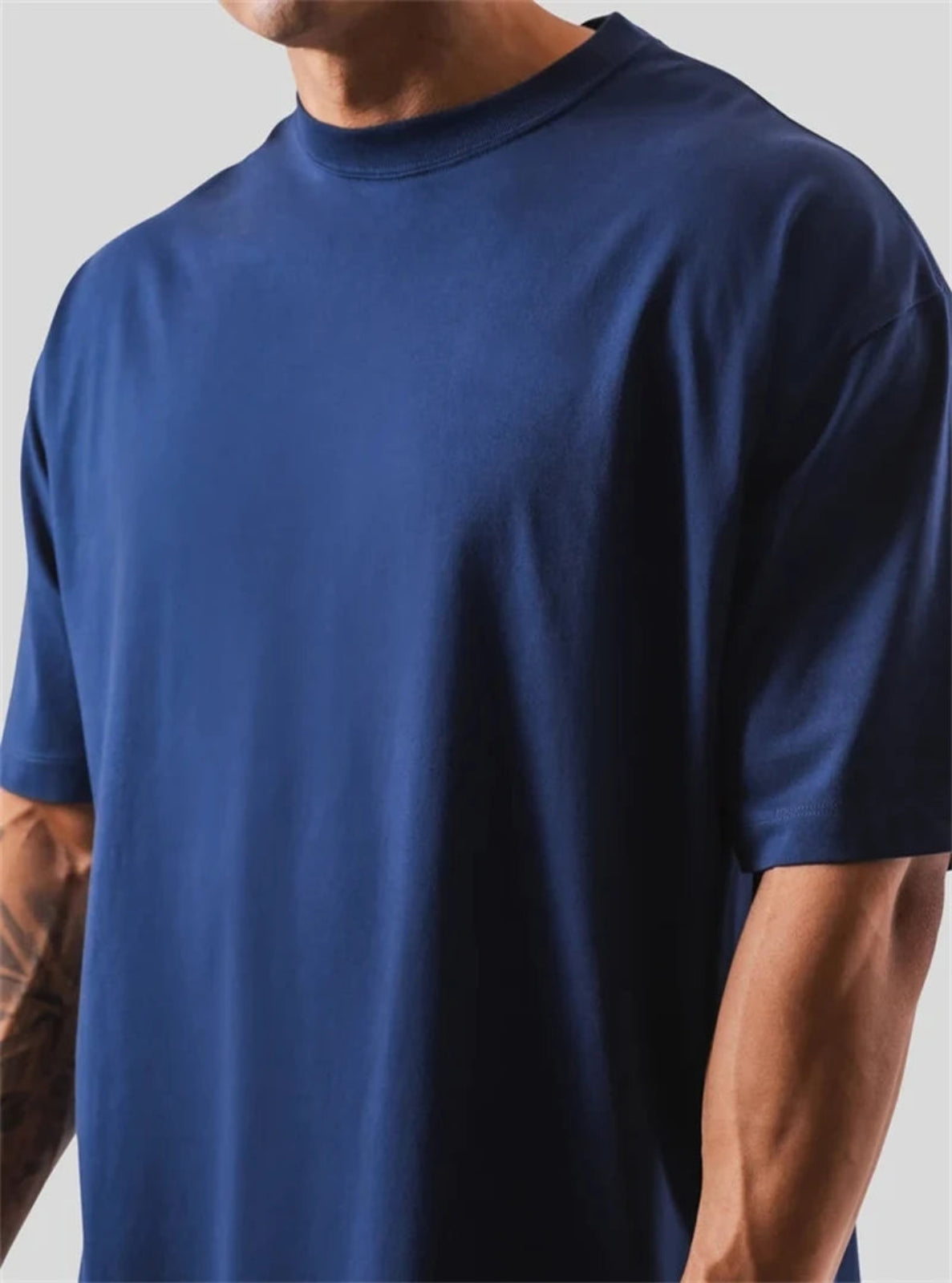 Person wearing a plain blue t-shirt against a neutral background