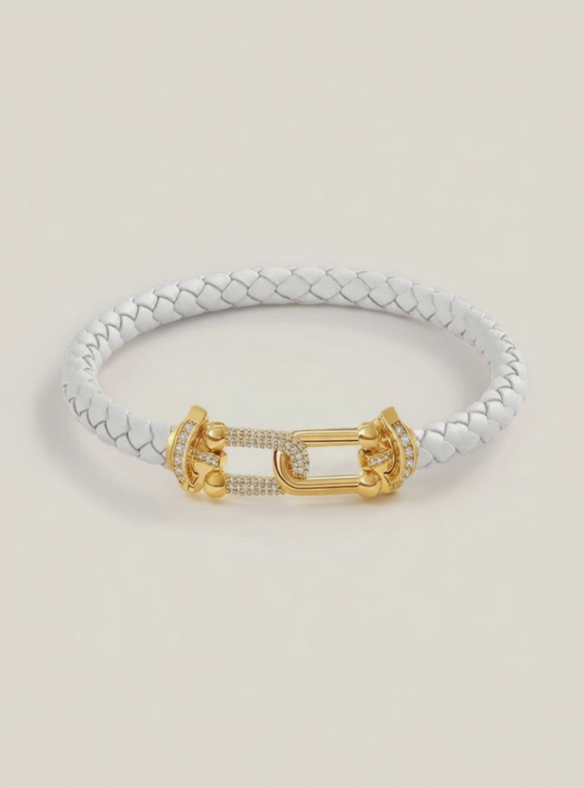 White braided bracelet with a gold clasp on a light beige background