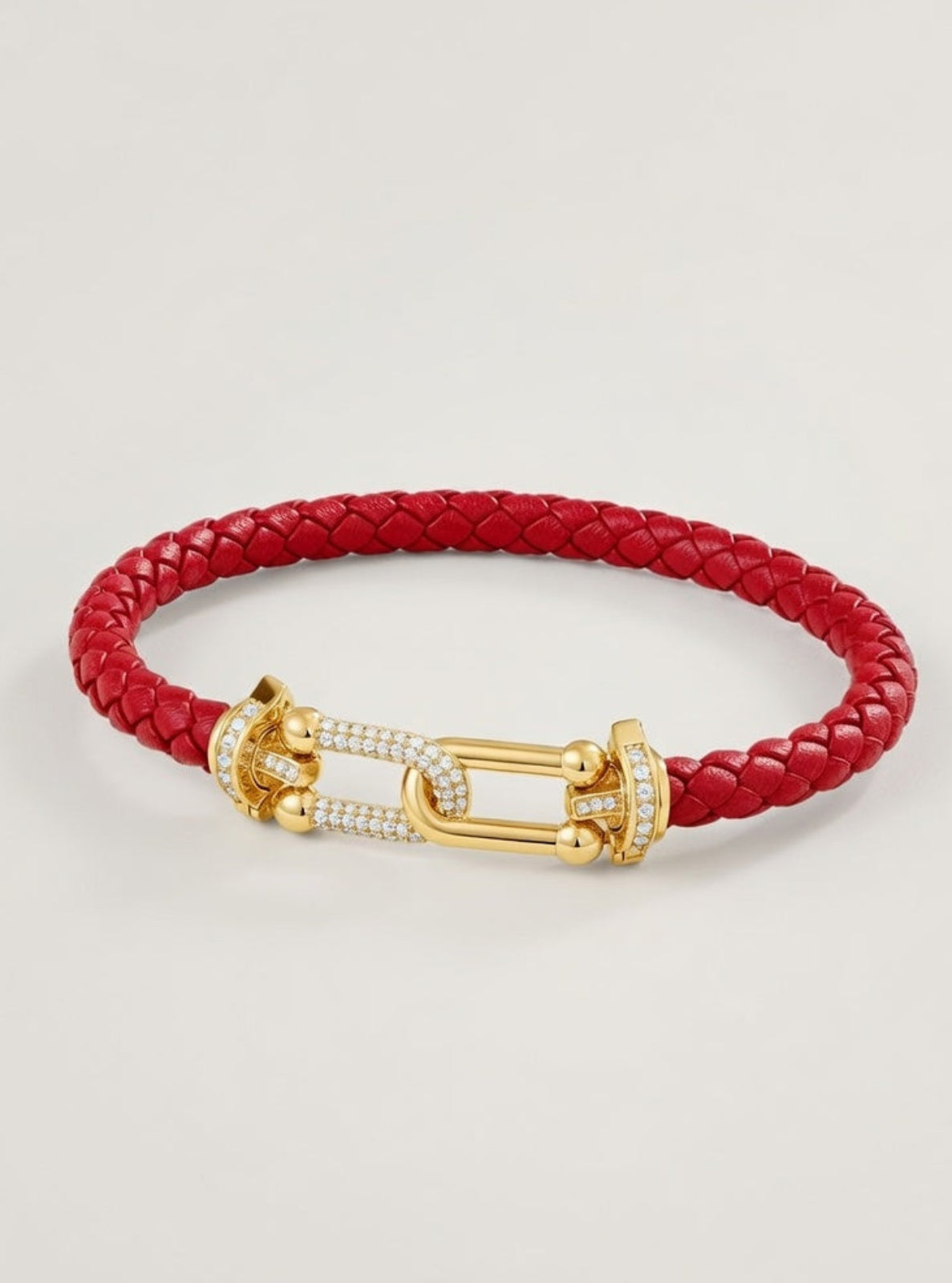 Red braided bracelet with a gold clasp on a light gray background