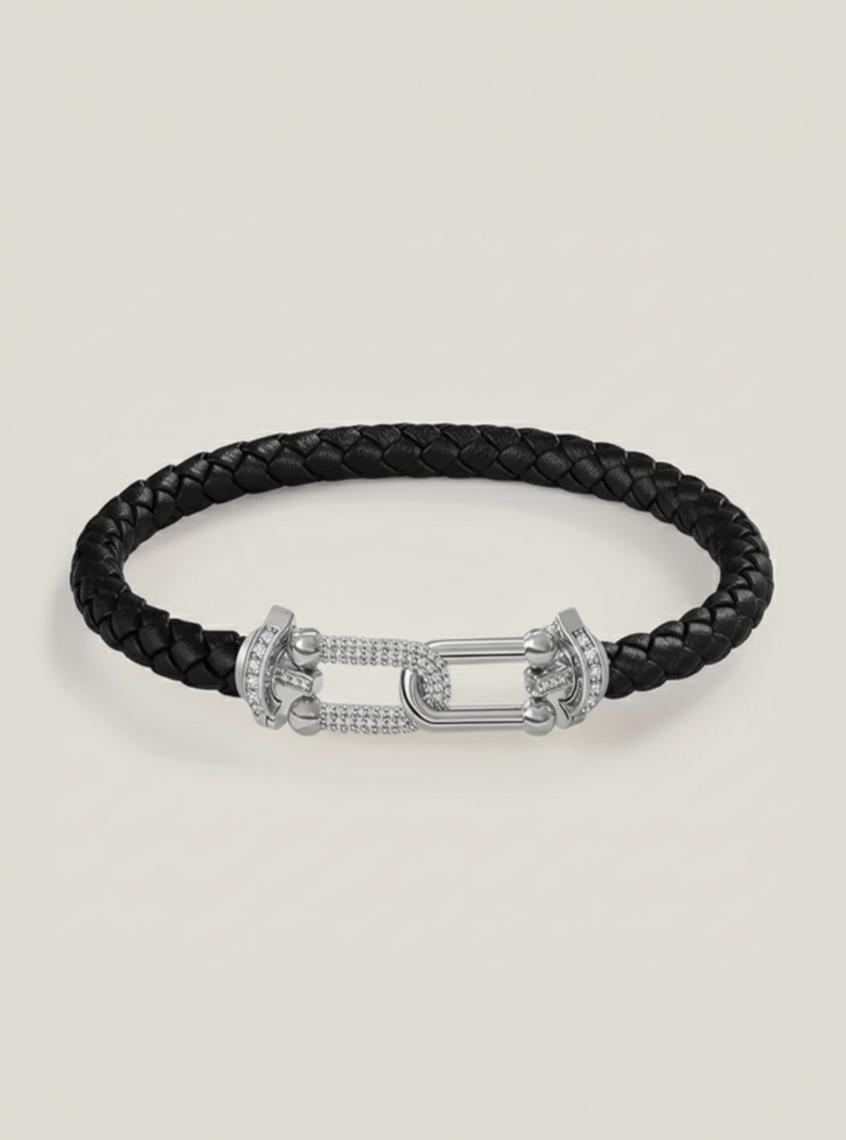 Black braided leather bracelet with silver clasp on a light beige background
