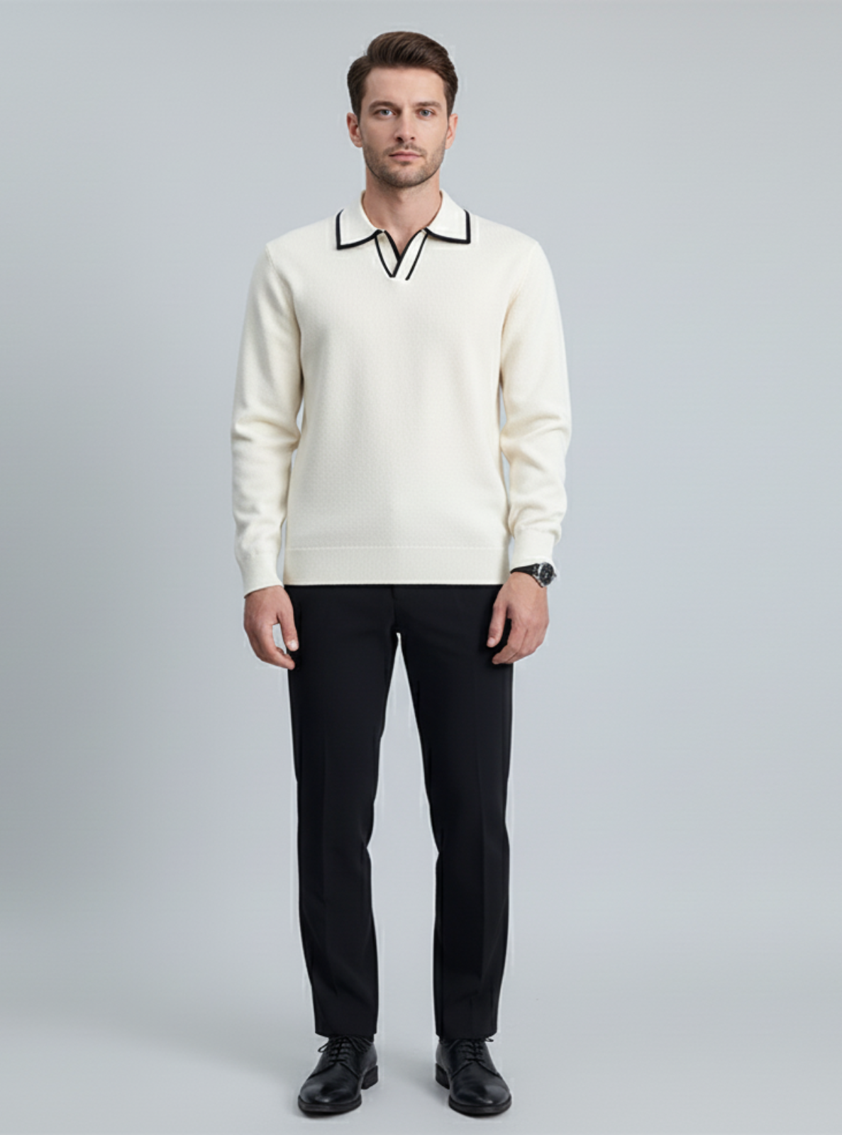 Man wearing a white sweater with black trim and black pants on a gray background