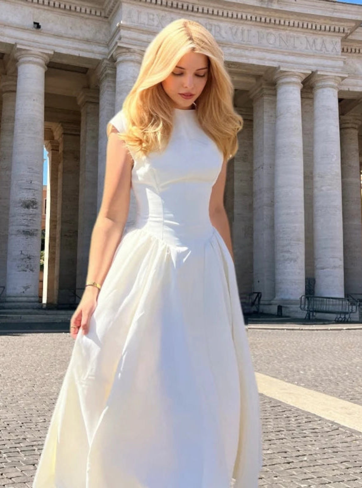 Woman in a white dress standing in front of classical architecture