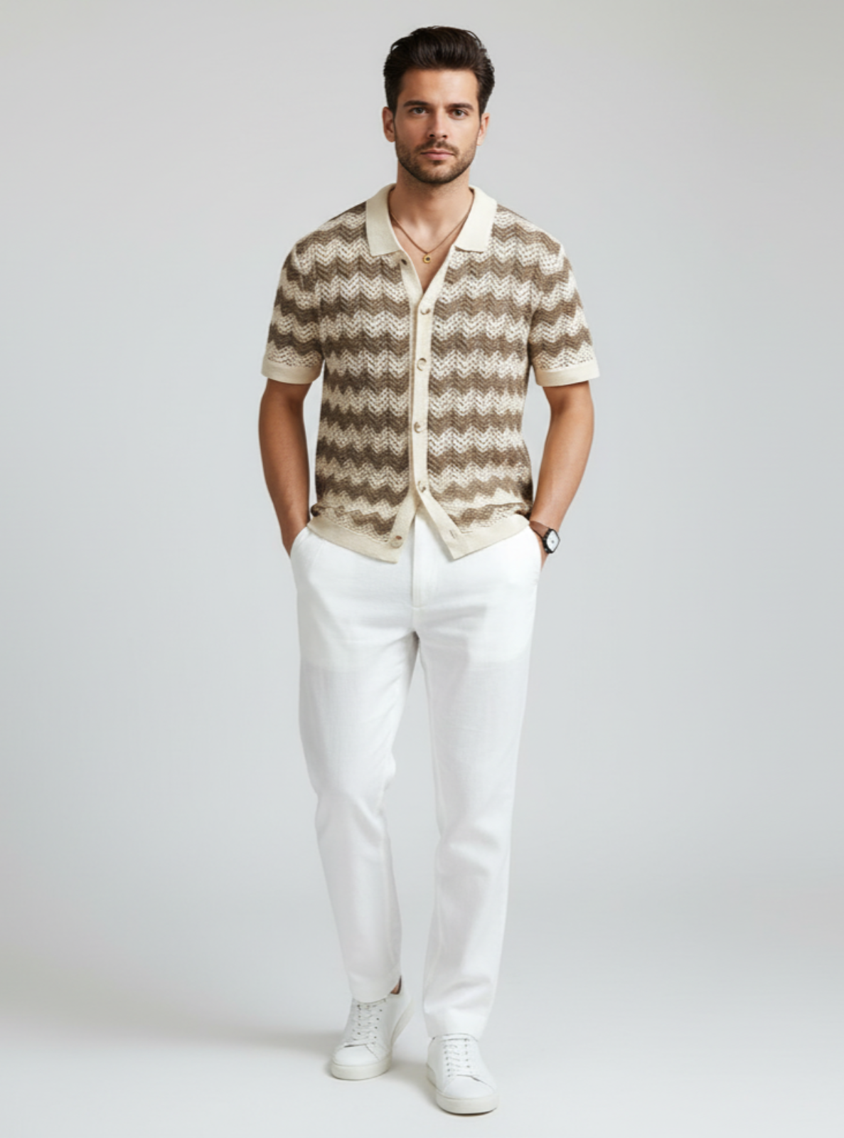 Man wearing a patterned shirt and white pants on a plain background